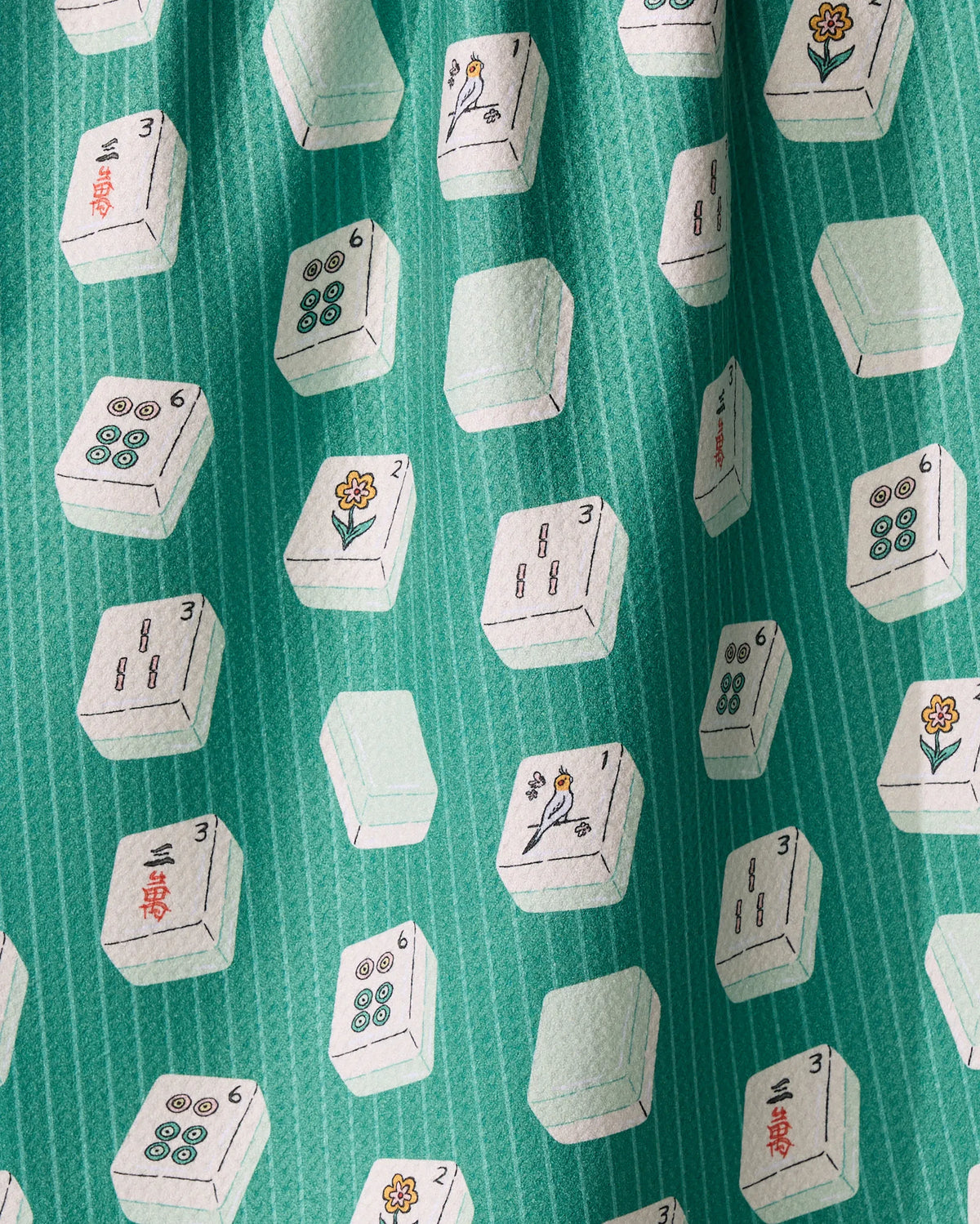 Ultra-absorbent green Tile Flow kitchen tea towel by Geometry, patterned with white mahjong tiles featuring illustrations of birds, flowers, and numbers.