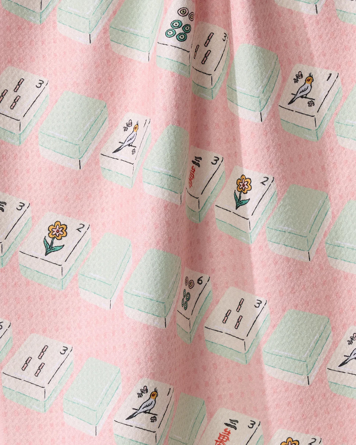Tile Parade quick-drying fabric in pink, patterned with illustrations of mahjong tiles featuring birds, flowers, and numbers.