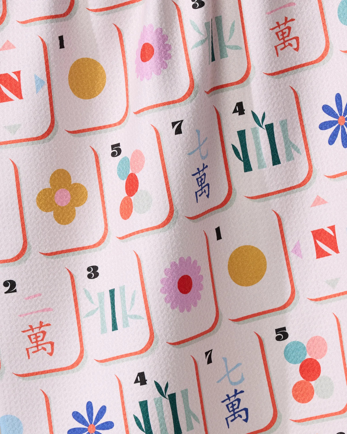 Geometry Tile Toss recycled fabric tea towel featuring a pattern of mahjong tiles decorated with colorful floral and geometric designs.