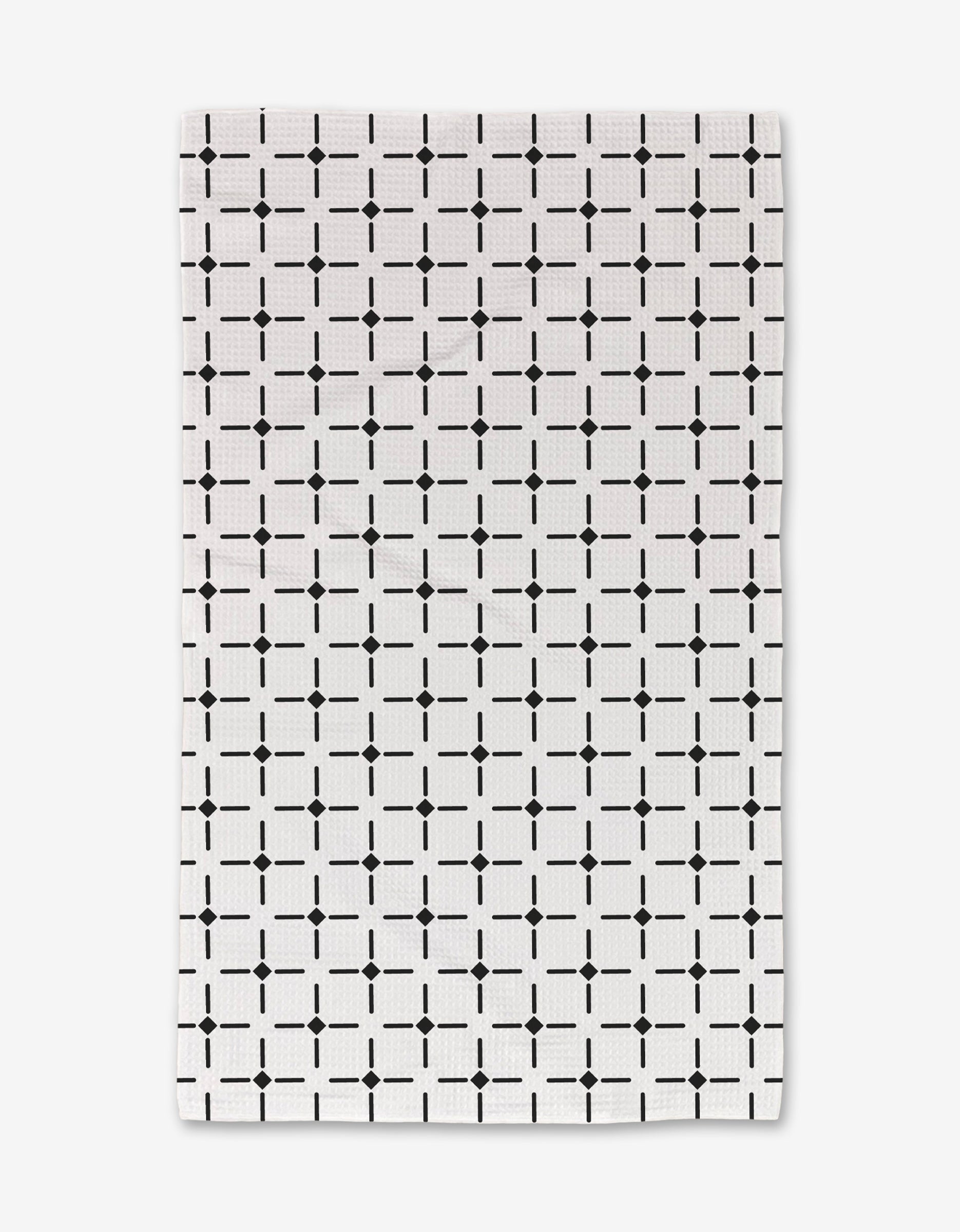 The Collins hand towel by Charlie Rowan Designs features a white background with a black geometric grid pattern and is crafted from ultra-absorbent material, offering both style and functionality.