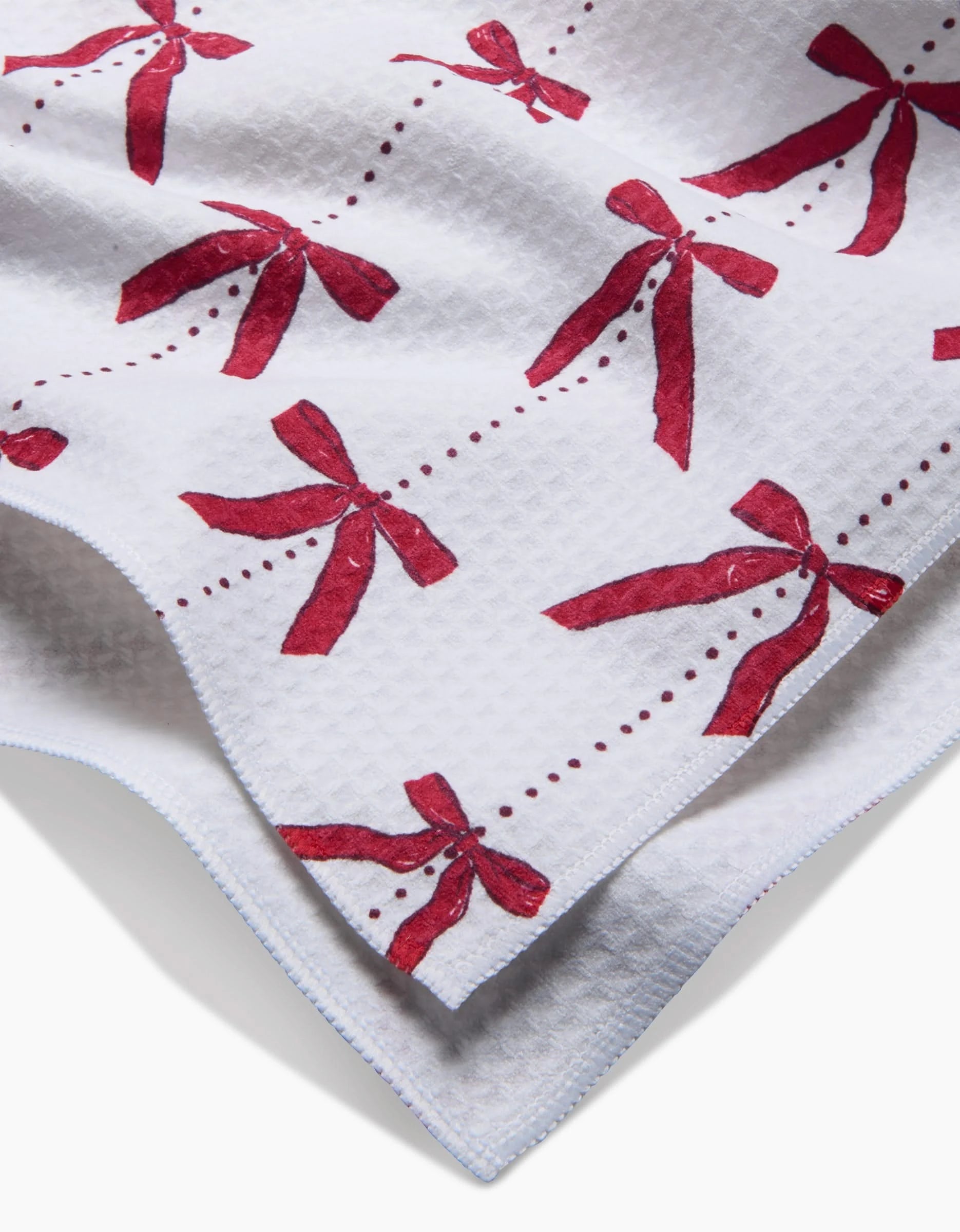 The Little Bows And Pearls Luxe Hand Towel by Hufton Studio features a white textured design with red bows and dotted lines, folded to display both sides. Made with Geoweave technology for extra softness and absorbency.