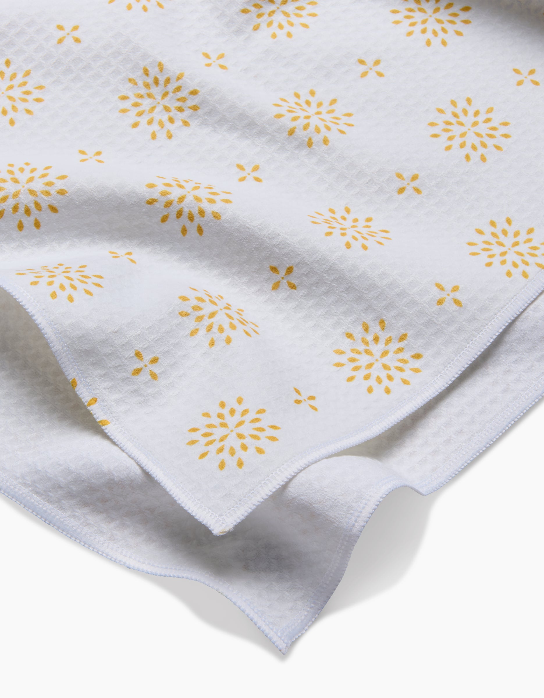Morning Petals by Danelys Sidron features white textured fabric with a subtle grid pattern and yellow floral prints. Ultra-absorbent, lightweight, and flexible—perfect for Luxe Hand Towels.