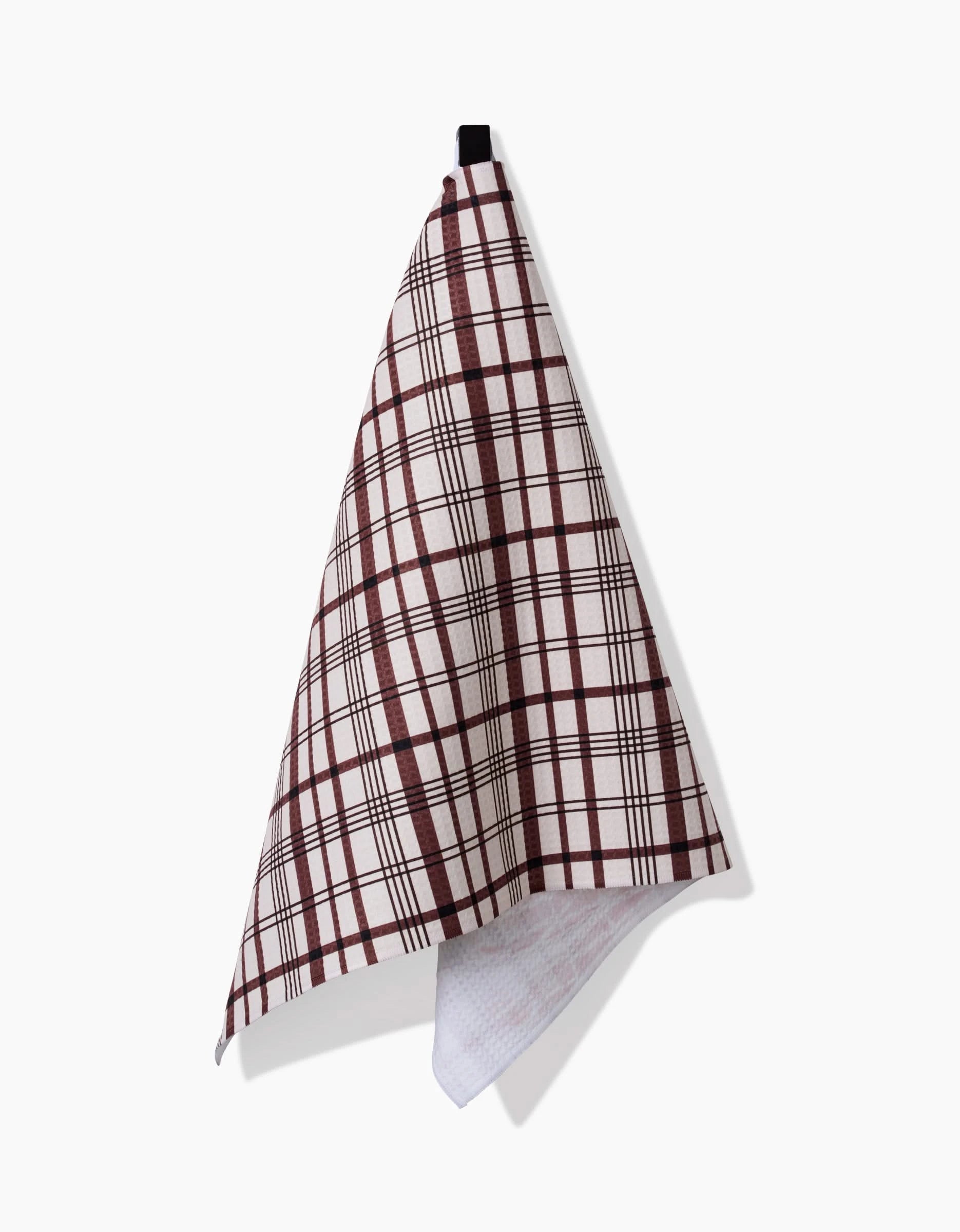 The Vintage Plaid Natural hand towel by Hufton Studio, featuring a red and black plaid pattern, hangs from a black loop against a white background. Made with Geoweave technology, this quick-drying towel adds style to any kitchen or bath.