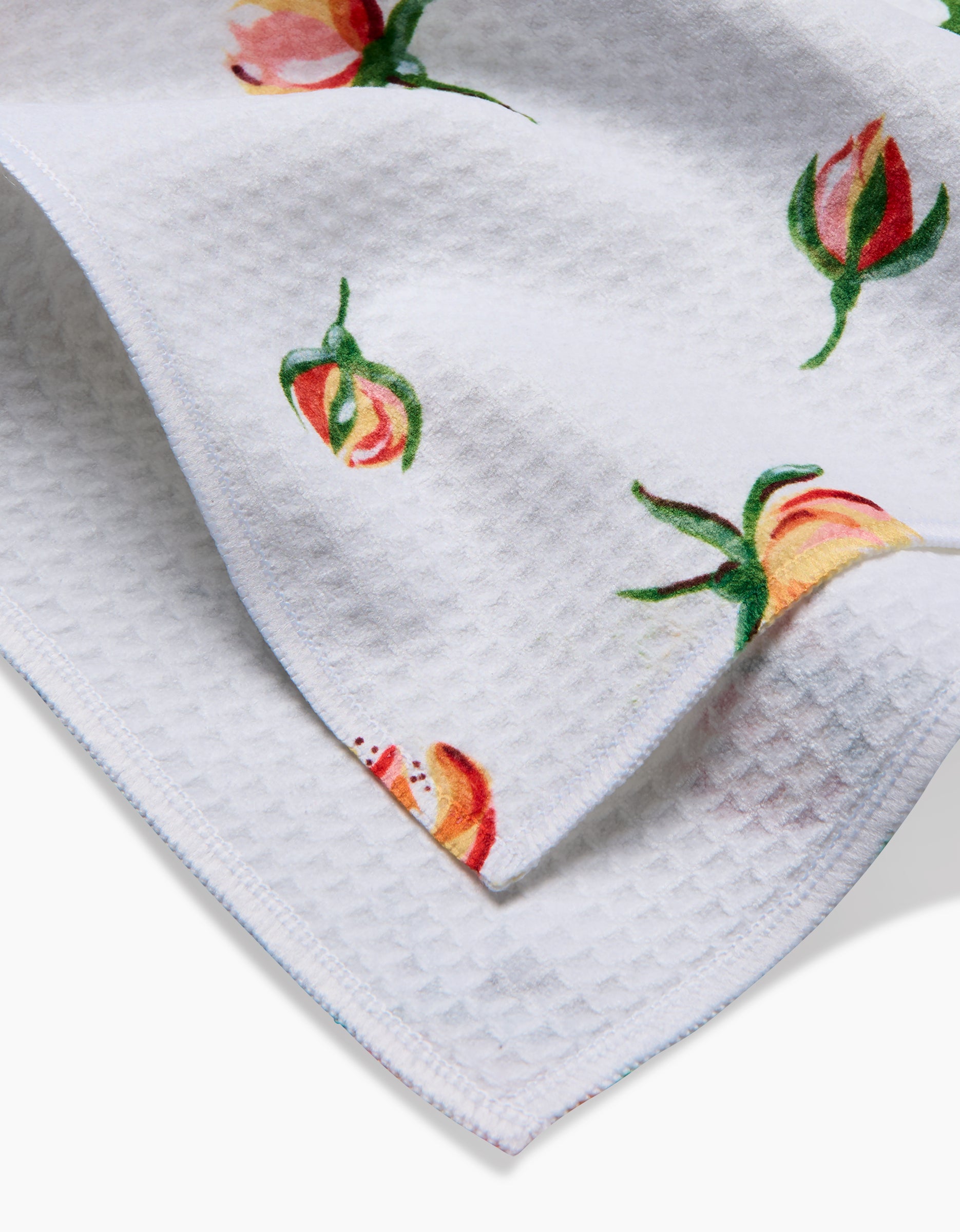 A close-up of the Linda Fox Yellow Rosebuds towel, an ultra-absorbent white waffle-textured hand towel featuring a colorful floral print—ideal for those seeking luxury and style.
