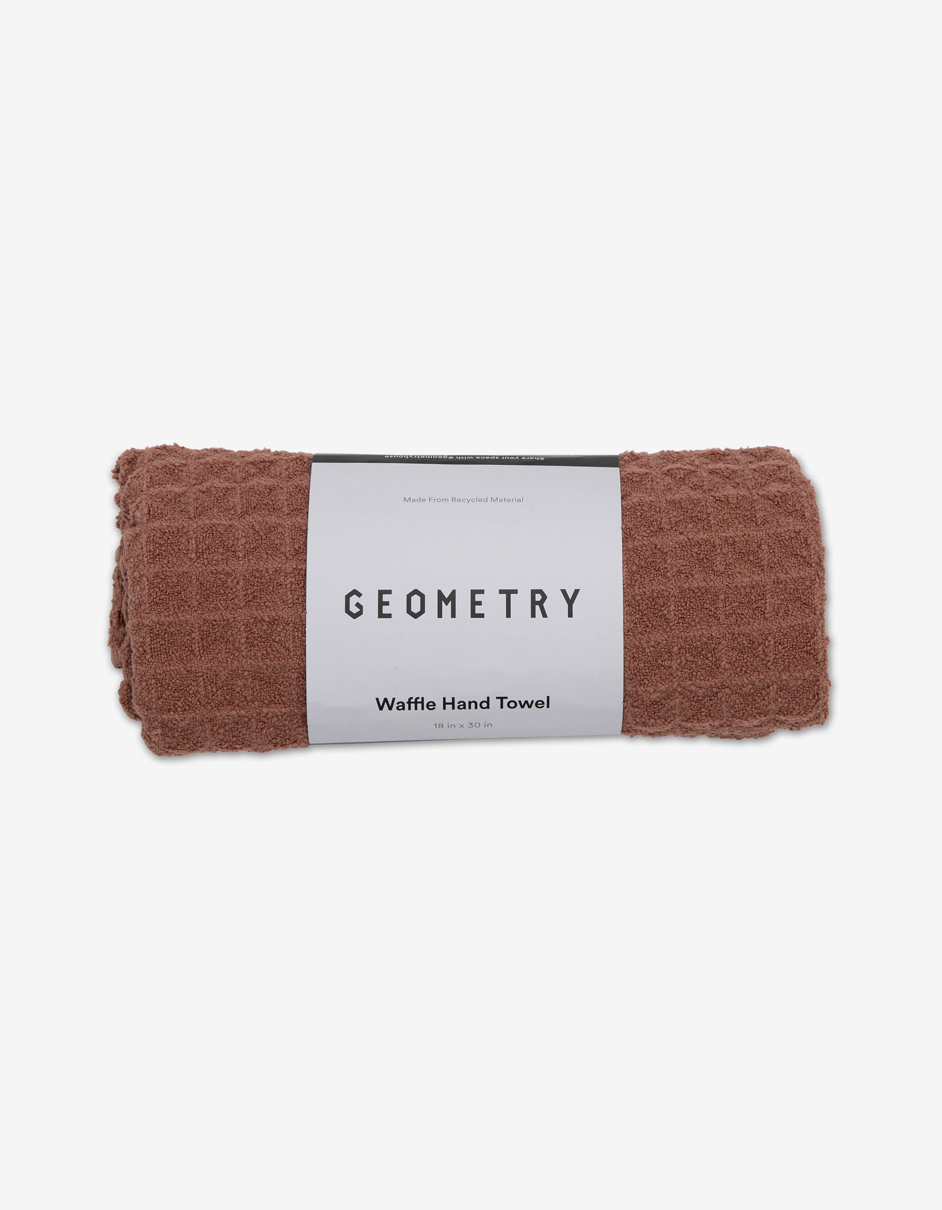 A rolled-up dusty rose ultra-absorbent waffle hand towel with a white label reading GEOMETRY Dusty Rose, exemplifying luxury towels against a plain background.