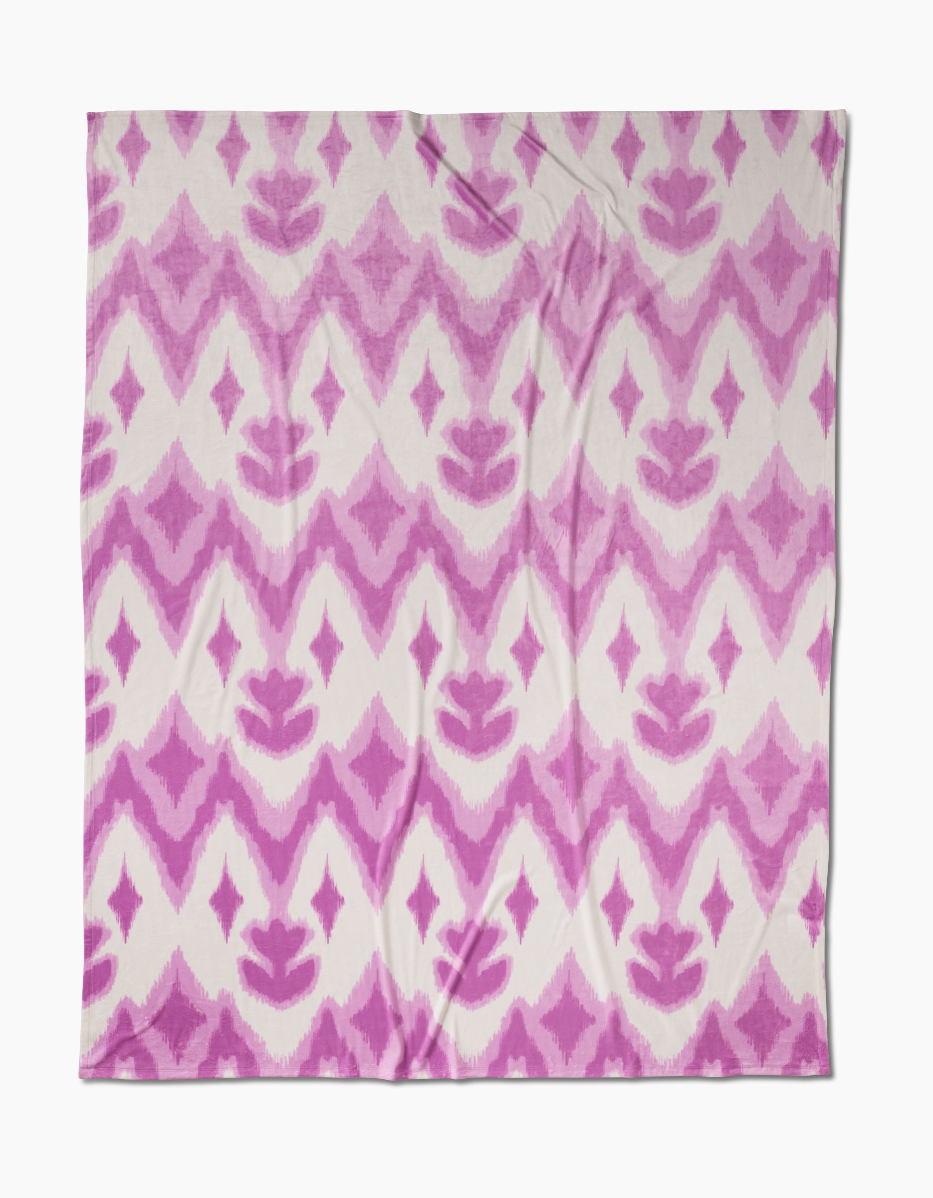 The Geometry Tulip Scatter Butter Blanket, square-shaped with a pink and white geometric ikat pattern of zigzags, diamonds, and floral motifs, is displayed flat on a white background. Made from recycled materials for added comfort.