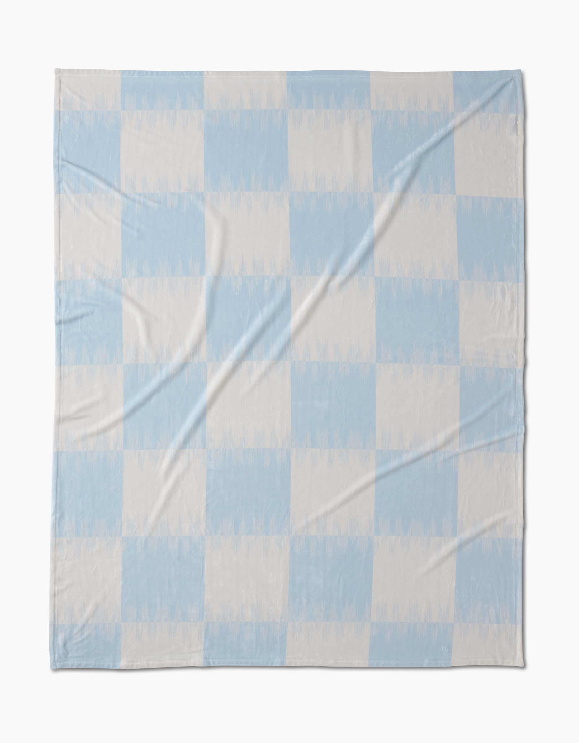 The Sweet Checks blanket by Geometry features a large, simple checkered pattern in pale blue and off-white. Made from recycled materials, its soft fabric with subtle wrinkles offers a cozy, sustainable bedding choice.