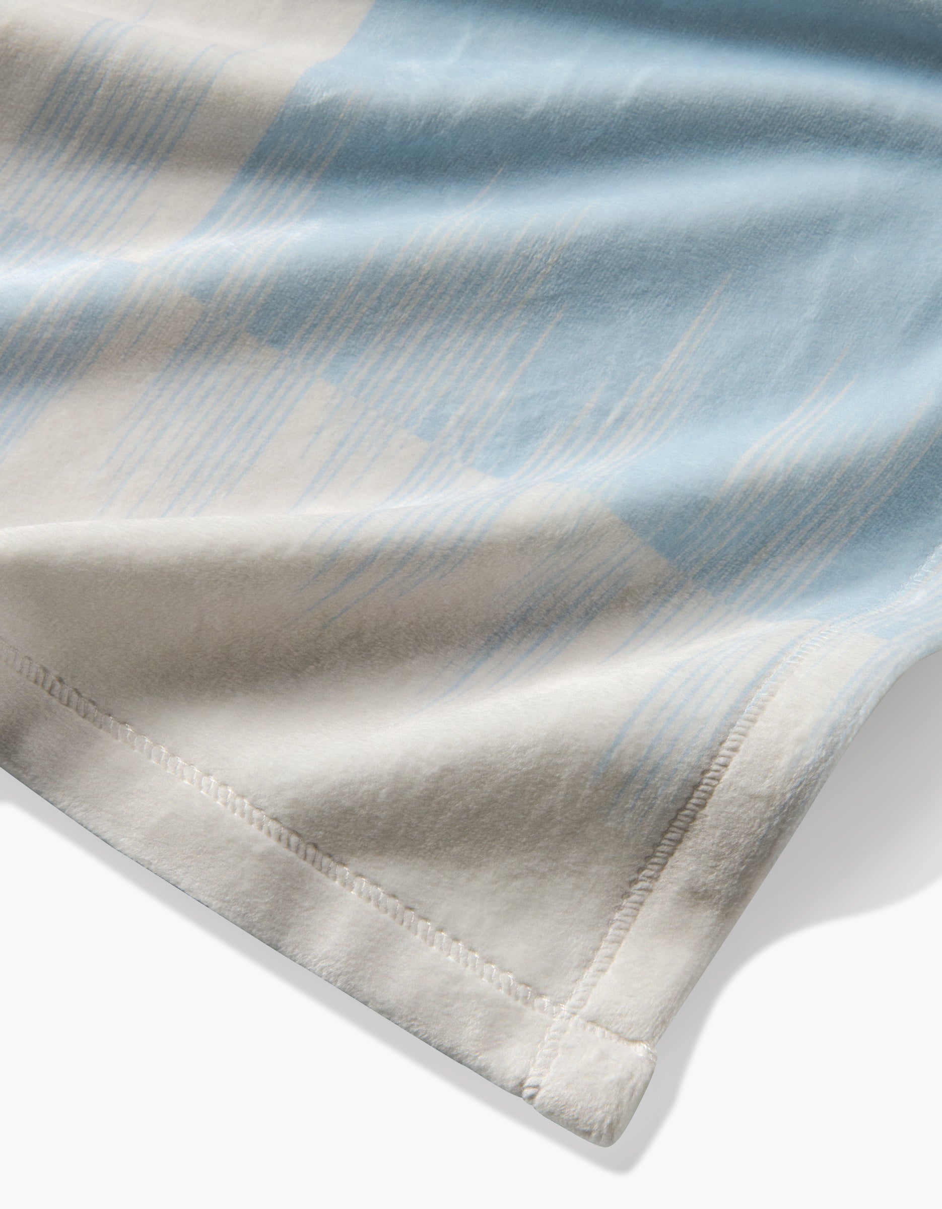 Close-up of Sweet Checks by Geometry, featuring blue and beige abstract patterns on a smooth, lightweight fabric with a stitched hem—ideal for sustainable bedding crafted from recycled materials.