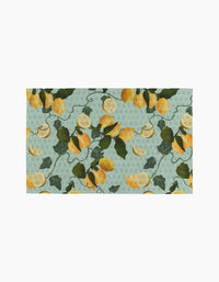 The Amalfi Lemons kitchen towel by Pascale Dilger is a rectangular, eco-friendly towel with yellow lemons, green leaves, and vines on a light blue dotted background.