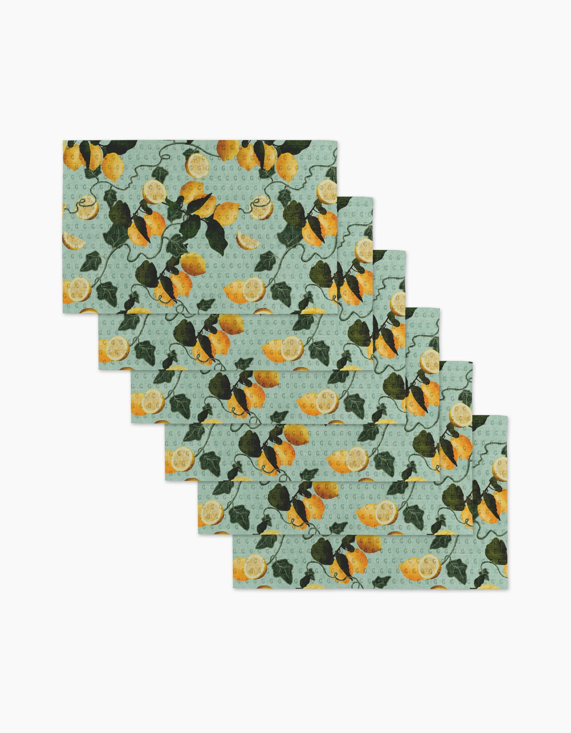 The Amalfi Lemons placemat set by Pascale Dilger includes six rectangular mats with a light blue-green background and a repeating lemon and green leaf pattern. Perfect for an eco-friendly kitchen, theyre neatly fanned in a stacked display.