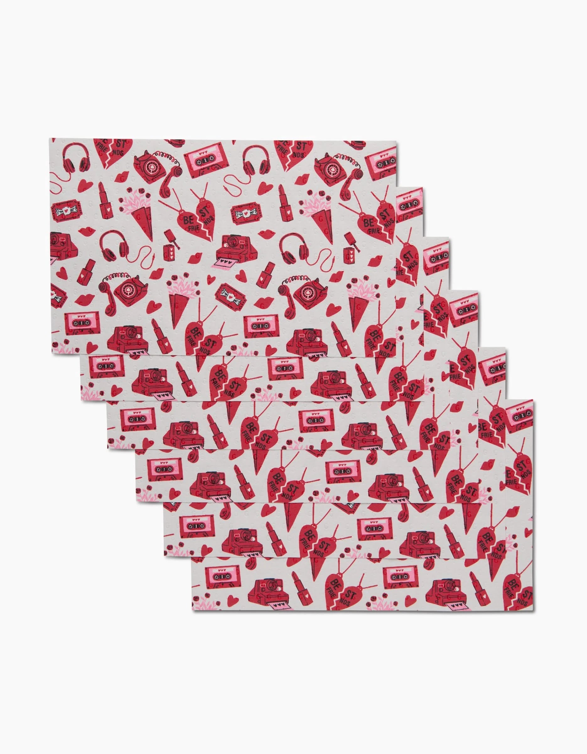 Six white rectangular Best Friends sheets by Charlie Rowan Designs, made from eco-friendly paper towels and decorated with red vintage cassette tapes, cameras, headphones, hearts, and eyes, are fanned out on a white background.