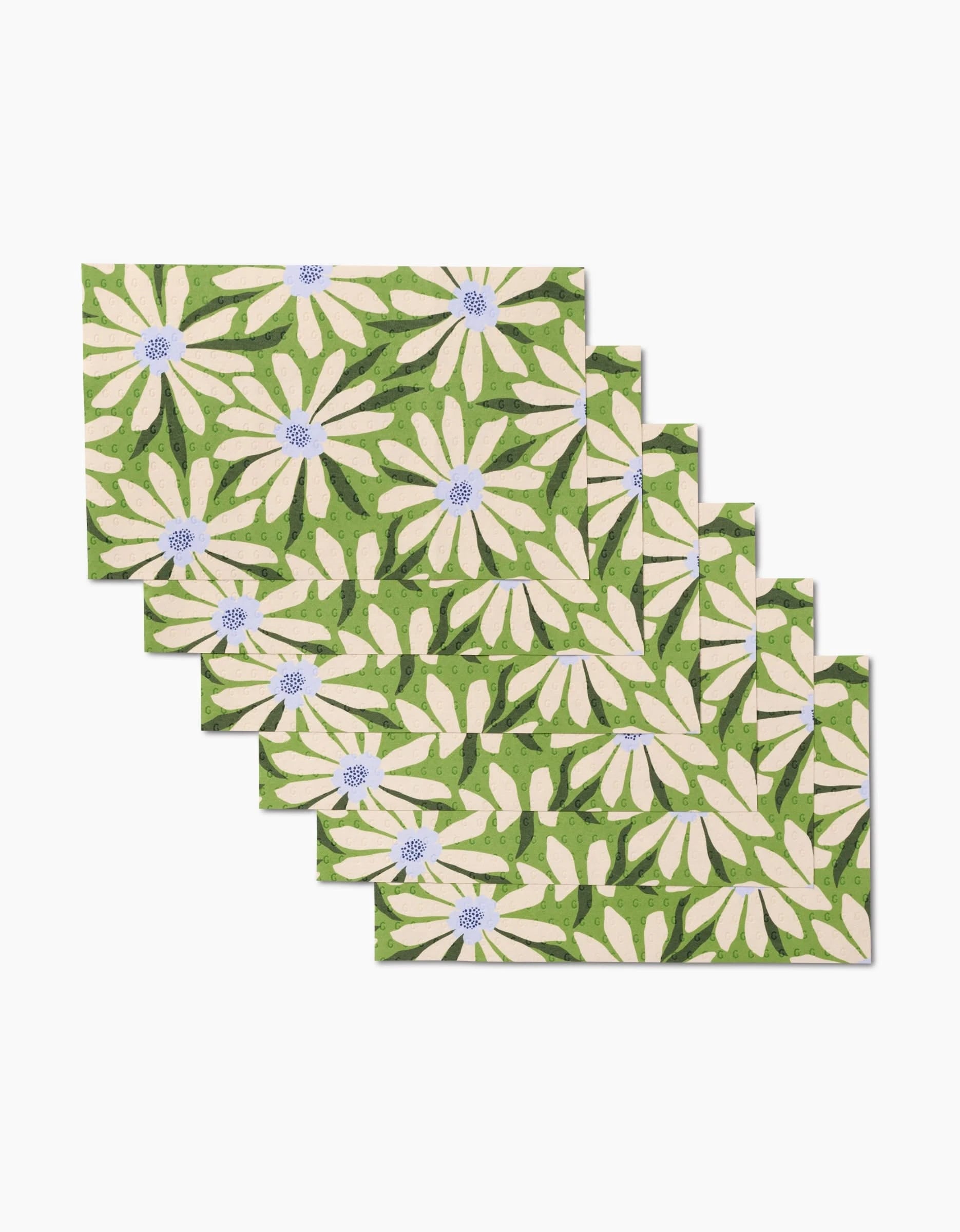 The GEOMETRY Bliss and Bloom set includes five rectangular placemats featuring white daisies with purple centers and green leaves on a green background, made from eco-friendly post-consumer recycled materials.