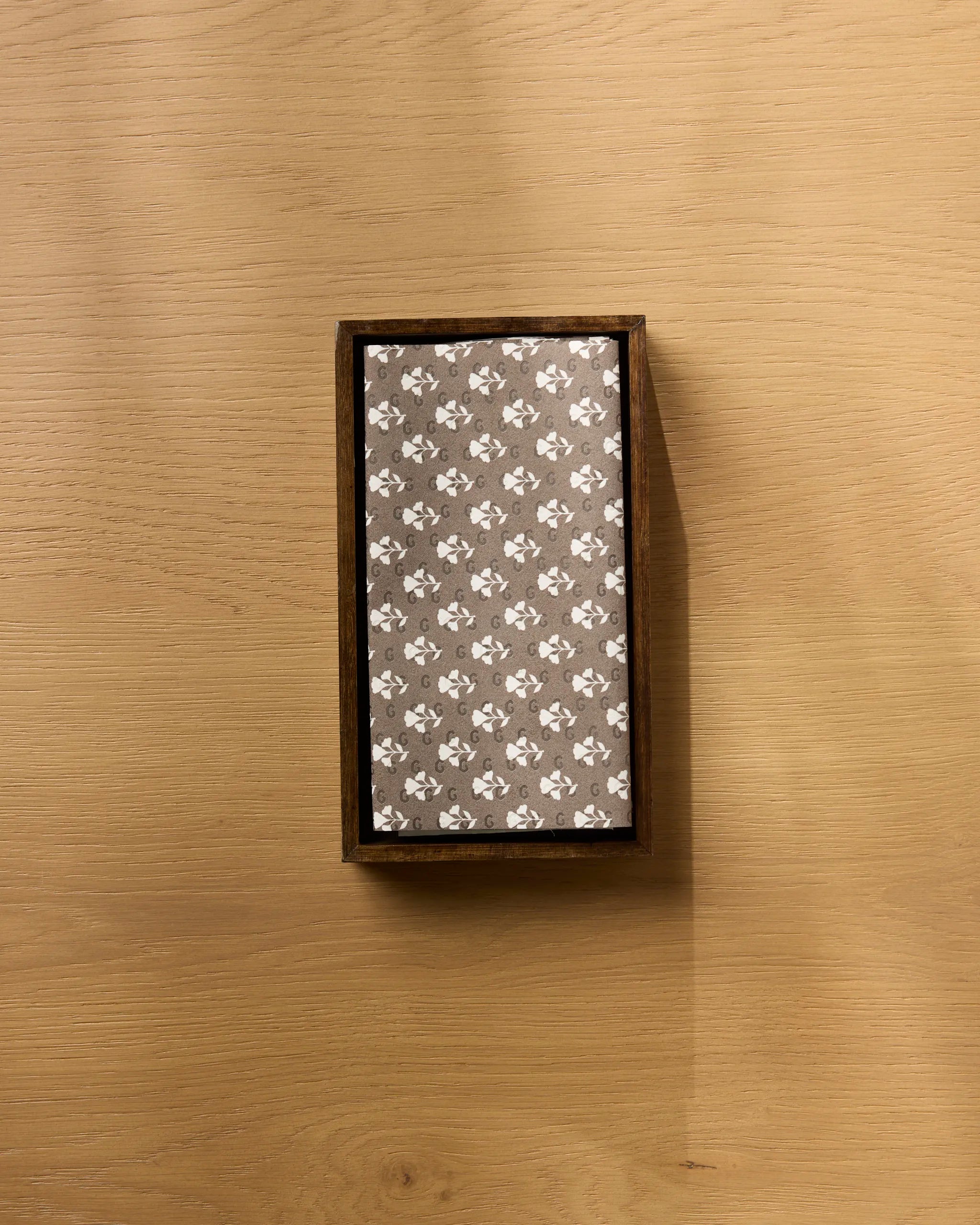 The Geometry "Bloom for Mom" rectangular box with a floral-patterned lid is ideal for storing eco-friendly kitchen towels and is displayed on a light wooden surface in an overhead shot.