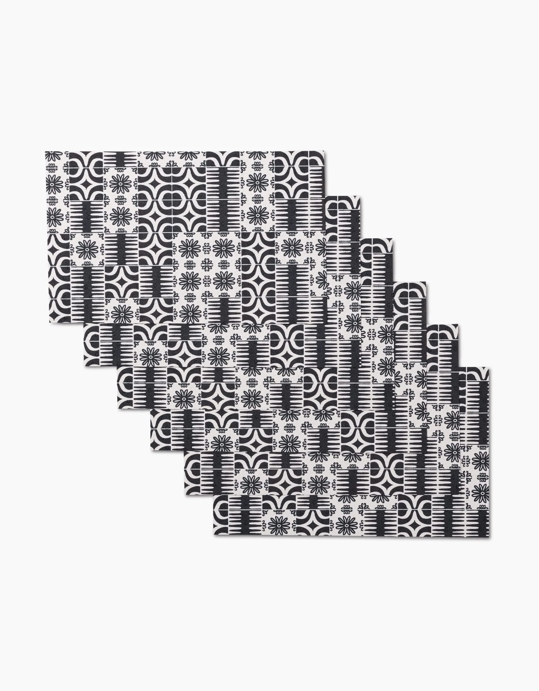 The GEOMETRY Bohemian Mosaic set includes eight reusable rectangular placemats, featuring a black and white geometric and floral pattern on a white background—an eco-friendly alternative to paper towels for your table.