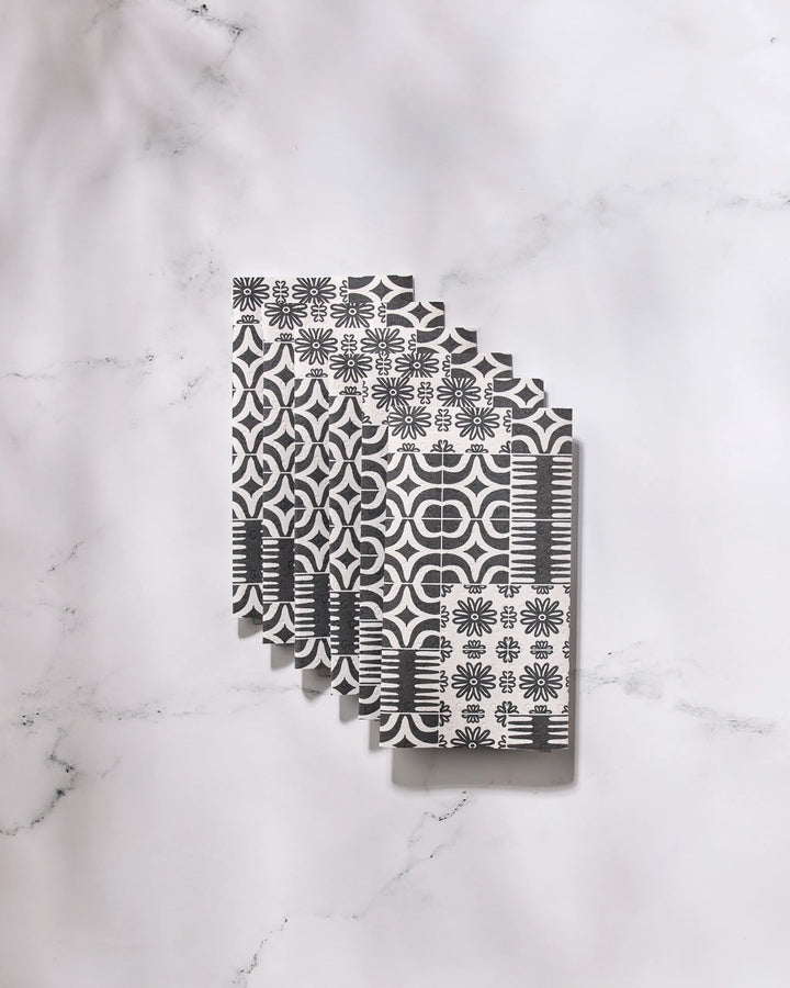 Five Bohemian Mosaic reusable paper towels by GEOMETRY, featuring black and white geometric and floral designs, are neatly fanned out on a white marble surface.