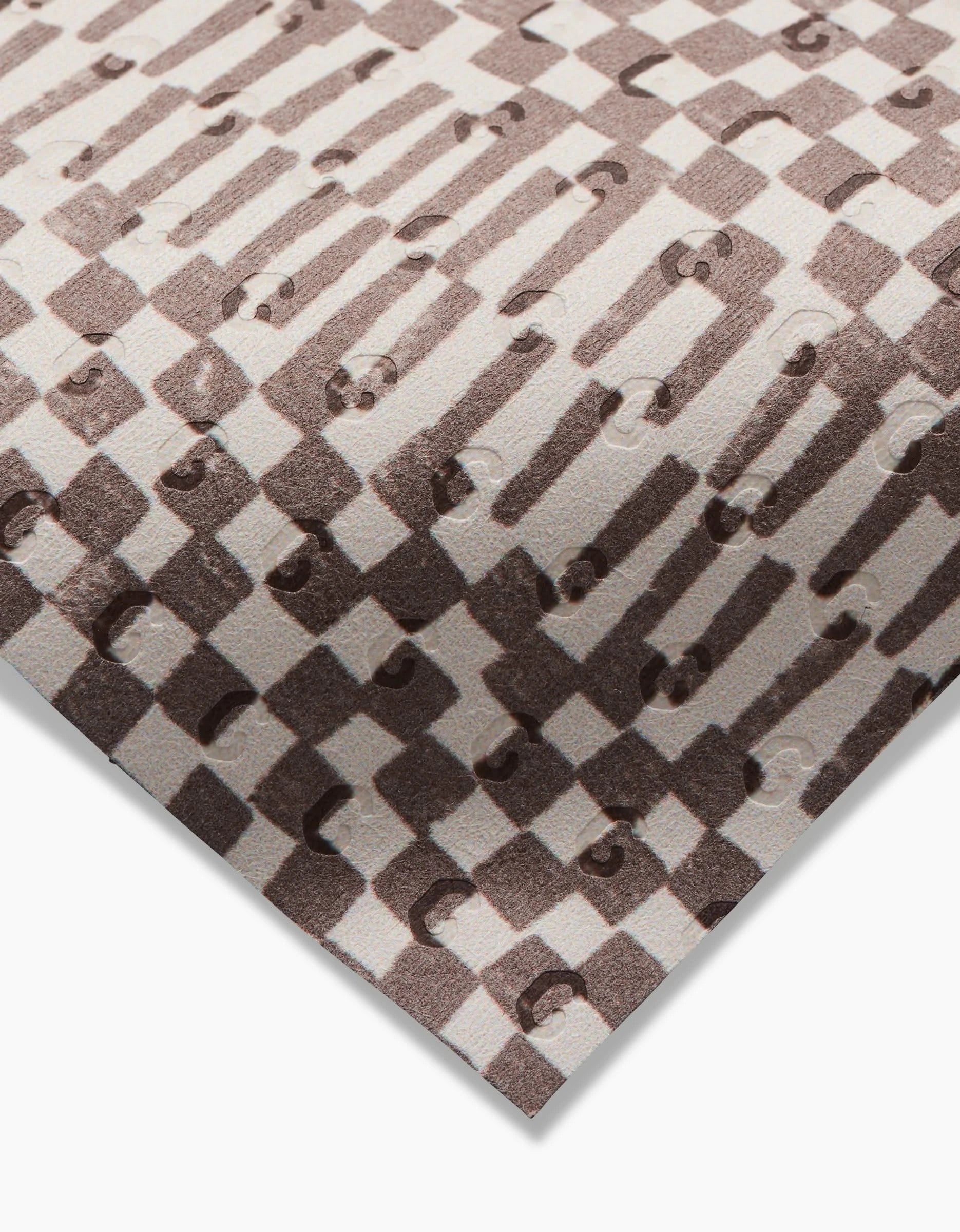 A close-up of Studio Jeannots Chutes Coffee packaging shows a brown and beige geometric checkerboard pattern with raised circular bumps, evoking eco-friendly textures like recycled paper towels.