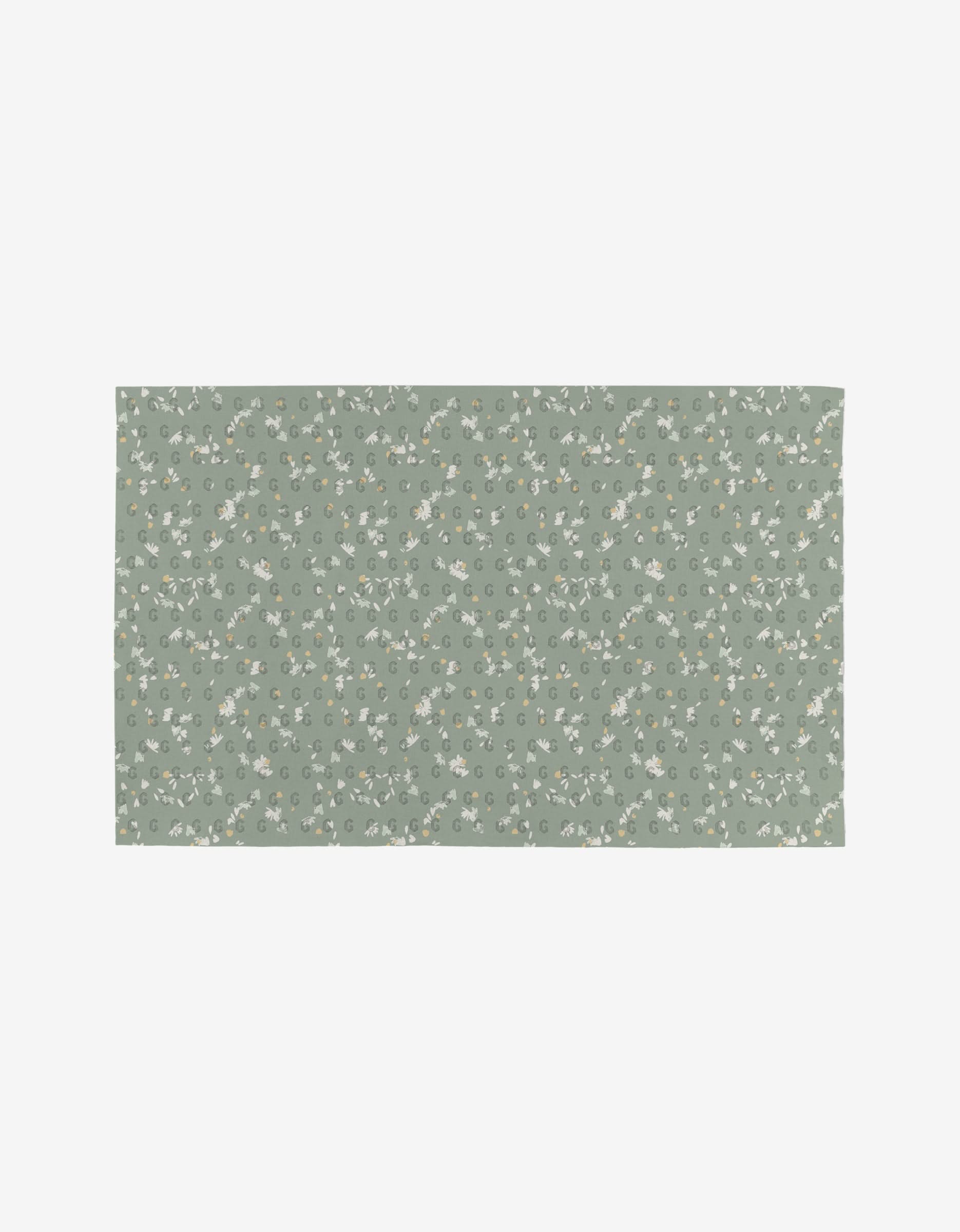 The Bunny Tea Time mat by Second Nature Studio is reusable and eco-friendly, with a muted green background featuring a delicate white and yellow floral pattern with green leaves evenly spread across its rectangular surface.