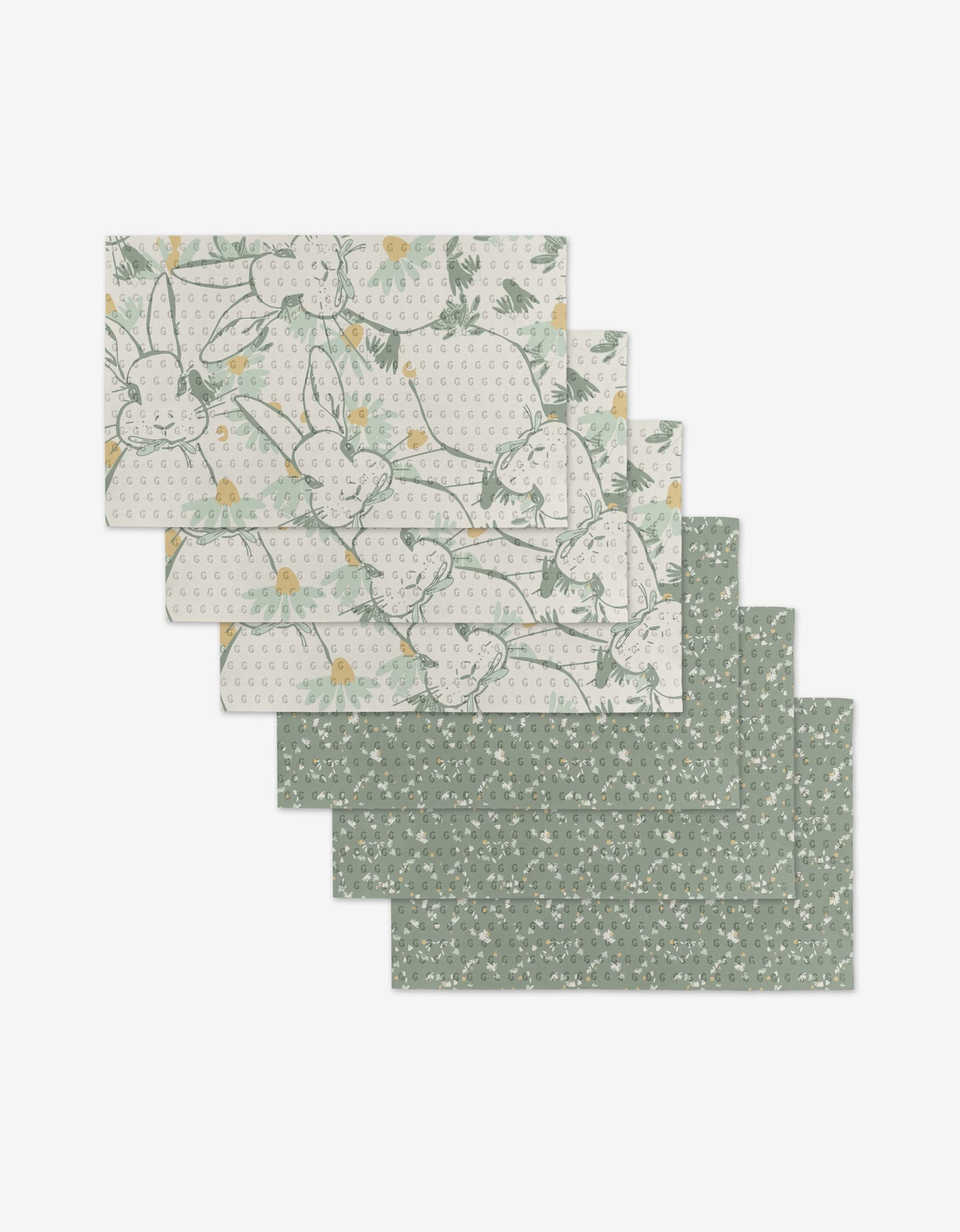 Six reusable Bunny Tea Time placemats by Second Nature Studio—three with green florals, three with line-drawn rabbits—feature soft green and yellow tones. Eco-friendly, not paper towels.
