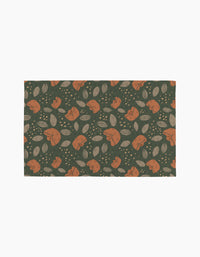 The Cali Sun mat by Amberleigh Adoff features orange rabbits, beige leaves, and dots on a dark green background for an eco-friendly touch inspired by reusable paper towels.