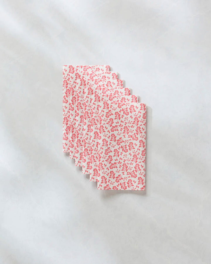 Five Carmine Garden cloth napkins by Danelys Sidron, featuring a red floral pattern on white, are fanned out on a marble-like surface—an eco-friendly kitchen towel alternative to paper towels.