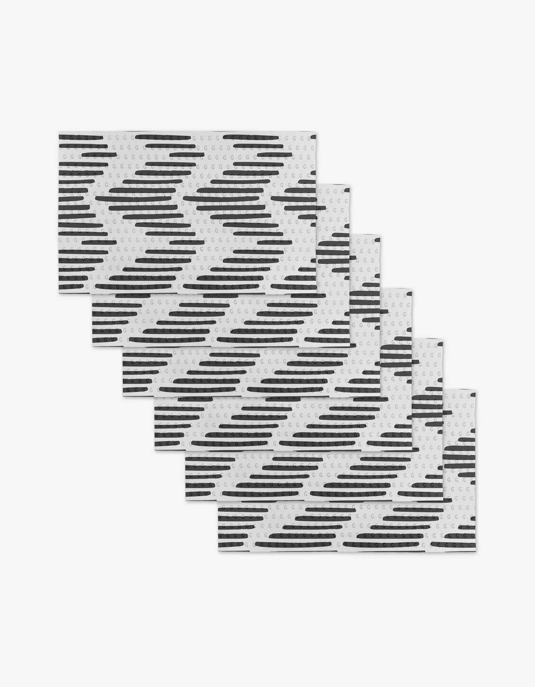 Five rectangular GEOMETRY Charlie Not Paper Towels featuring a black zigzag and striped pattern are arranged in a staggered, overlapping stack on a plain white background—an eco-friendly alternative to traditional paper towels.