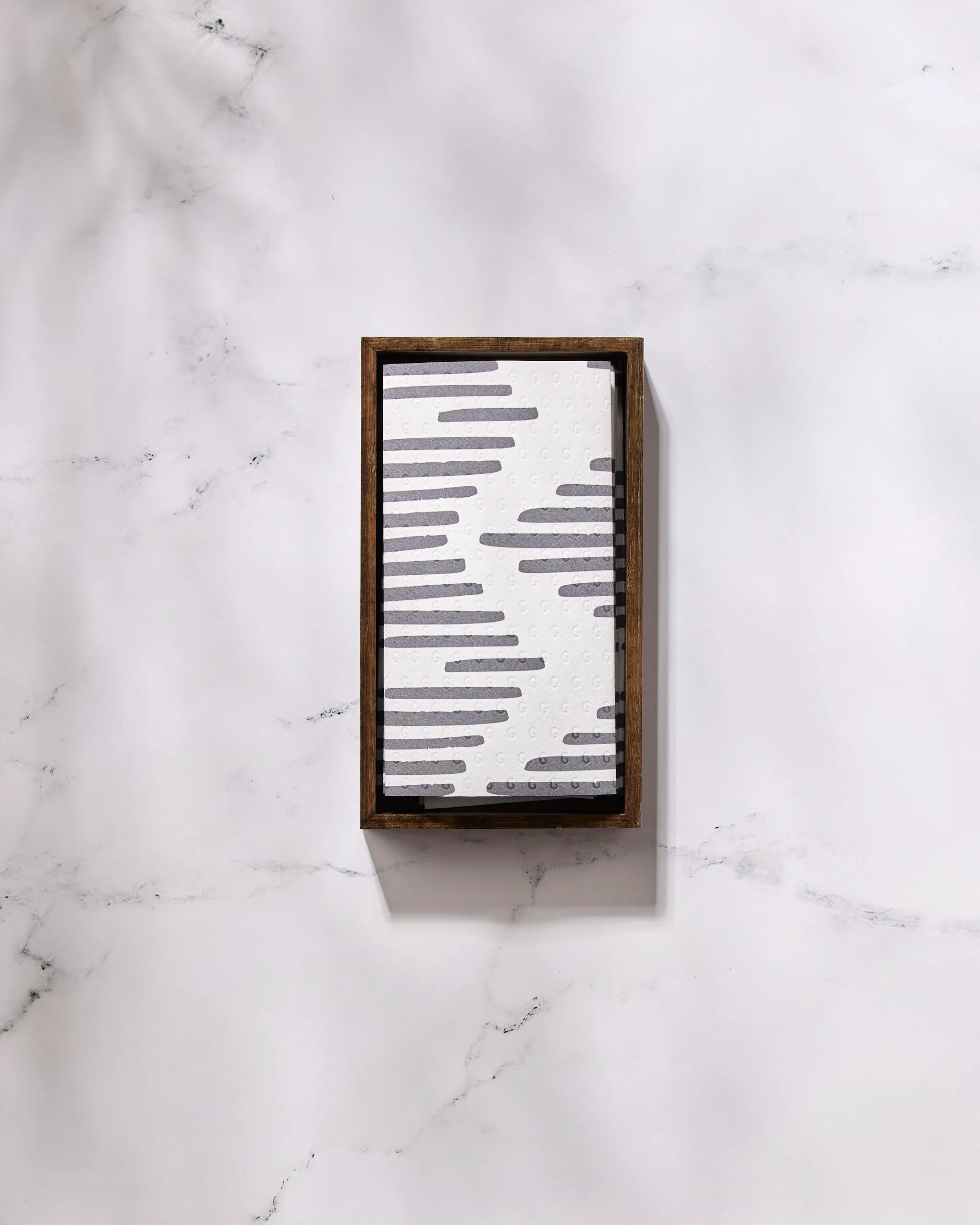 Charlie by GEOMETRY is a rectangular tray with a wooden frame and a white surface patterned with staggered black lines, ideal for showcasing eco-friendly kitchen towels. Shown here on a white marble background.