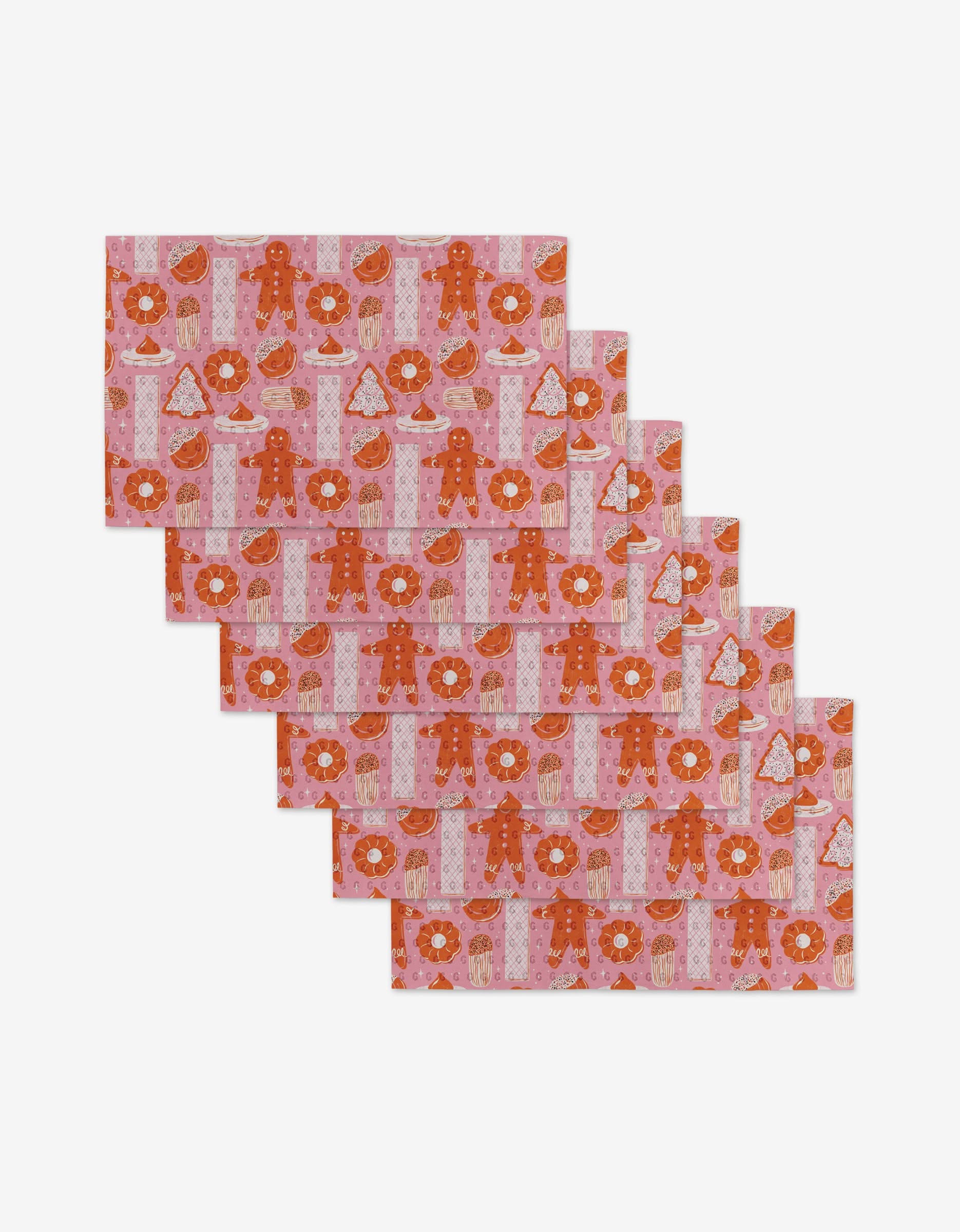 Set of six Christmas Cookies rectangular placemats by Megan Roy, featuring pink and red gingerbread men, donuts, Christmas trees, and cake slices—made from eco-friendly post-consumer recycled materials.