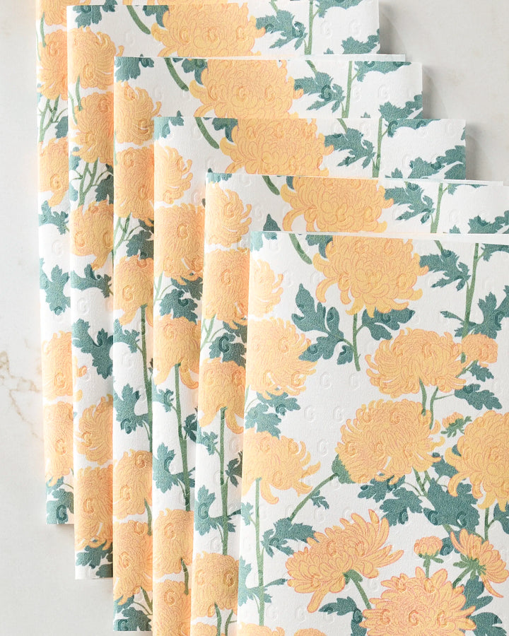 Five eco-friendly "Chrysanthemum" kitchen towels by Vaishali Design Studio, featuring a repeating yellow and orange floral pattern with green leaves, displayed in a fanned stack on a light background.