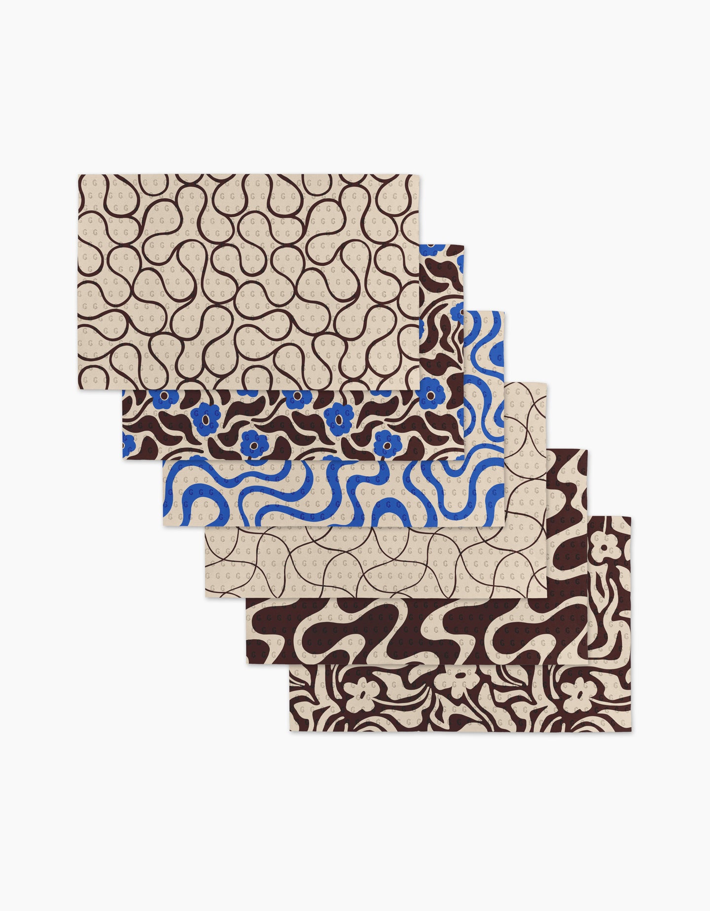 Five Coffee Reverie placemats by Gerdadzy, each with unique abstract and floral motifs in brown, beige, and blue, are fanned out. Made as an eco-friendly recycled paper towel alternative for sustainable style.