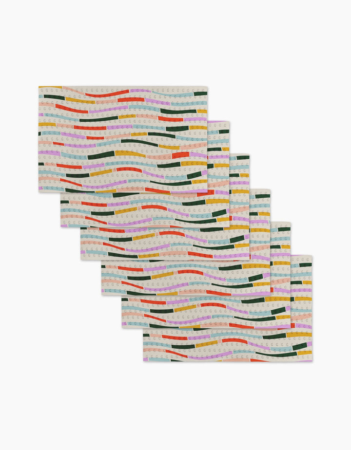 Six Colorful Currents rectangular placemats by Geometry feature wavy green, yellow, red, orange, and pink stripes on a light background—made from eco-friendly post-consumer recycled materials and arranged in a fanned-out stack.