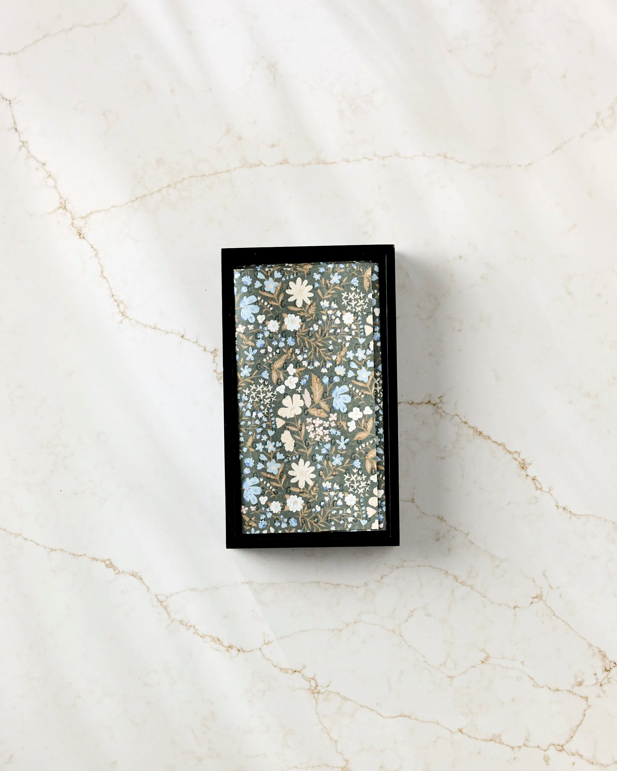 The Danelys Sidron Cottage Meadow Sepia eco-friendly kitchen towels feature a blue, white, and beige floral pattern with black borders, presented in a rectangular box on white marble with subtle brown veining.