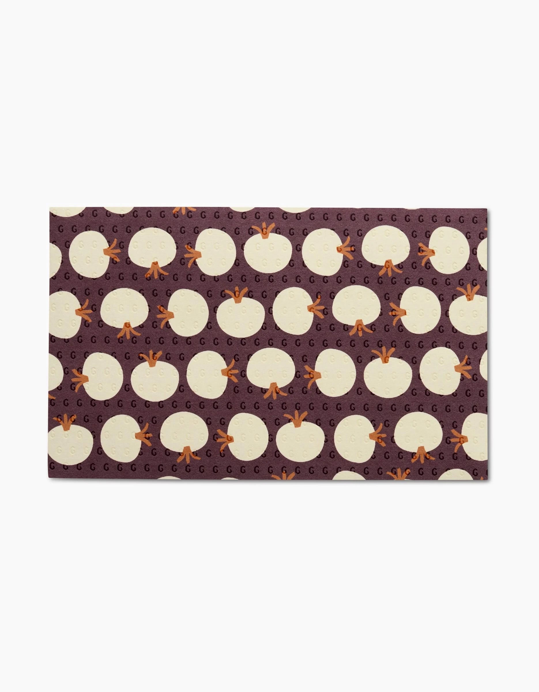 Add vibrant color to your kitchen with the Dancing Fall mat by Lizzie Clark, featuring white eggs, orange chicken feet, and small G letters on a dark purple background—perfect for pairing with reusable paper towels.