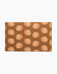 The Dancing Fall doormat by Lizzie Clark features a brown background with orange and white pumpkins and scattered letter Gs—an eco-friendly, charming accent that pairs perfectly with reusable paper towels for your sustainable home.