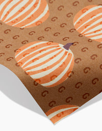 The Lizzie Clark Dancing Fall reusable paper towel is brown and eco-friendly, featuring an orange and white striped pumpkin pattern with subtle “G” shapes and a slightly curled corner.
