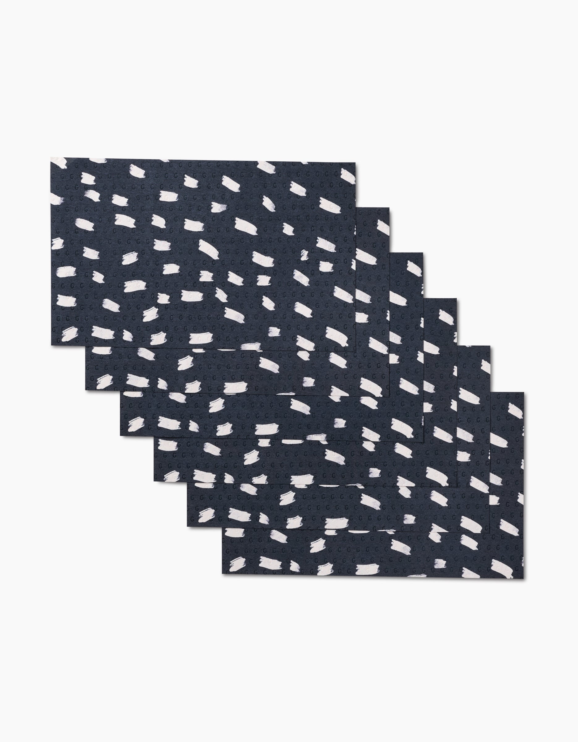 Six GEOMETRY Dark Out placemats in navy blue, each rectangular with an abstract white dashed pattern, made from eco-friendly post-consumer recycled materials, stacked slightly askew against a white background.