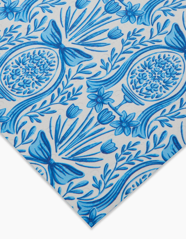 A close-up of the Delft Blue Easter Eggs and Bunnies fabric by Sarah Daugherty shows a blue floral and botanical pattern with intricate flowers, leaves, and bow-like shapes on white—ideal inspiration for reusable paper towels.
