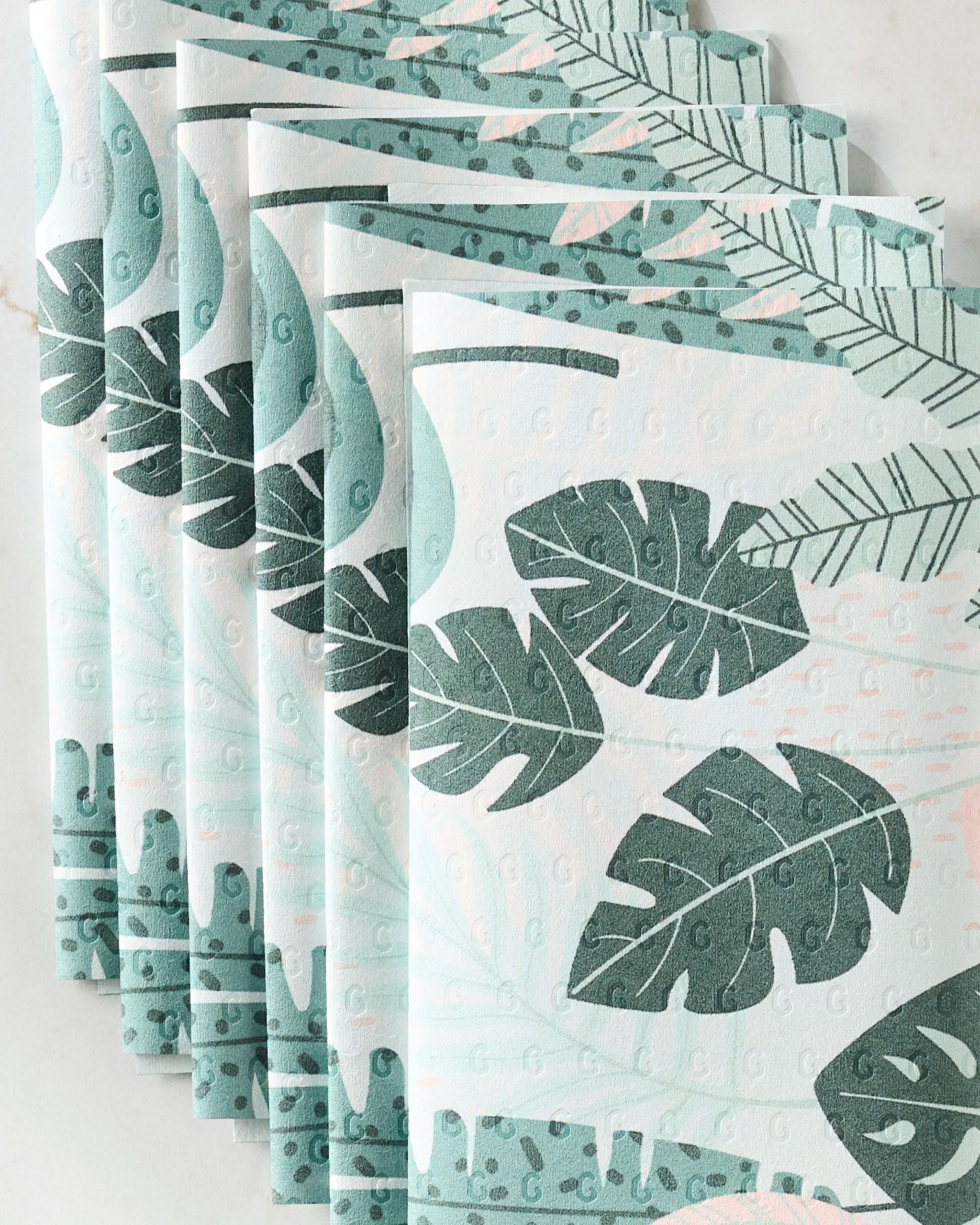 The Diedre paper towels by GEOMETRY are eco-friendly and feature a green tropical leaf pattern with overlapping leaf shapes on a white background.