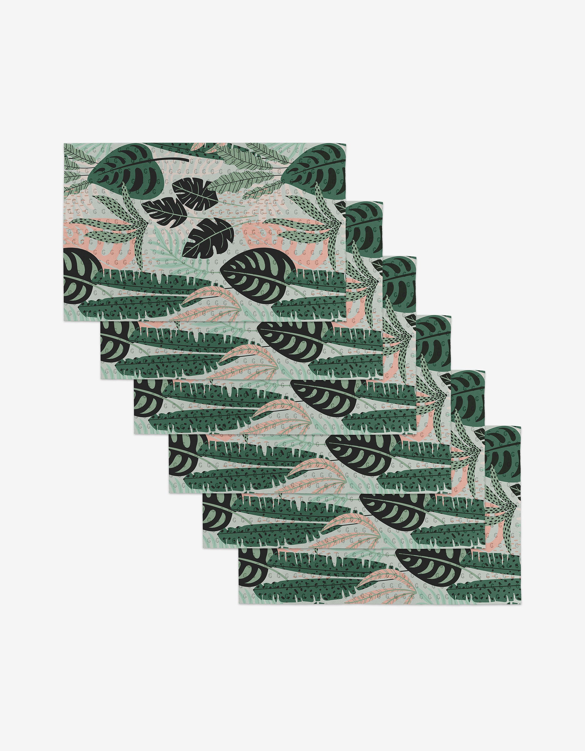 Six rectangular Diedre placemats by GEOMETRY, featuring a tropical leaf print in green, black, and light pink, are arranged in a step-like overlap on white—a reusable, eco-friendly alternative to paper towels.