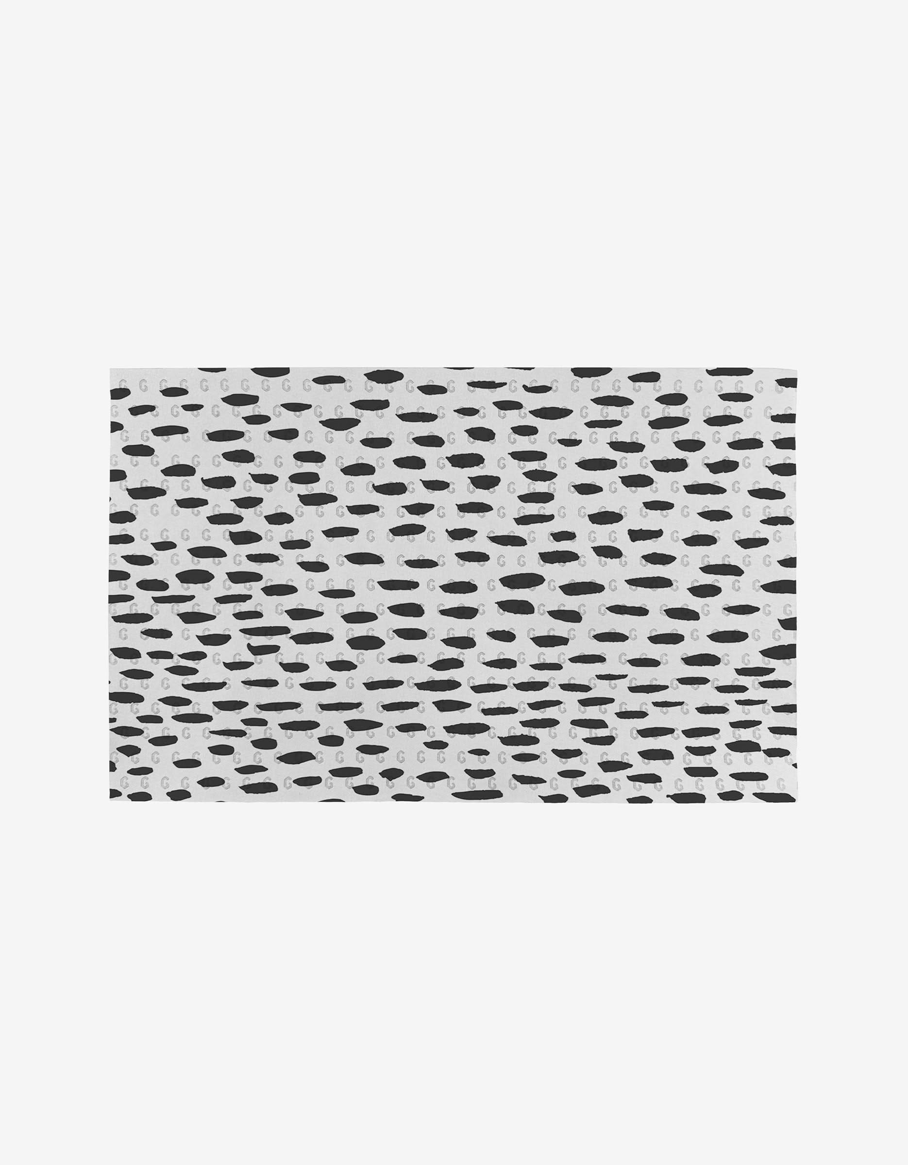 Dot Dash by GEOMETRY features a rectangular surface with an irregular pattern of black ovals and dash-shaped spots on a white background, inspired by reusable paper towels for an eco-friendly touch.