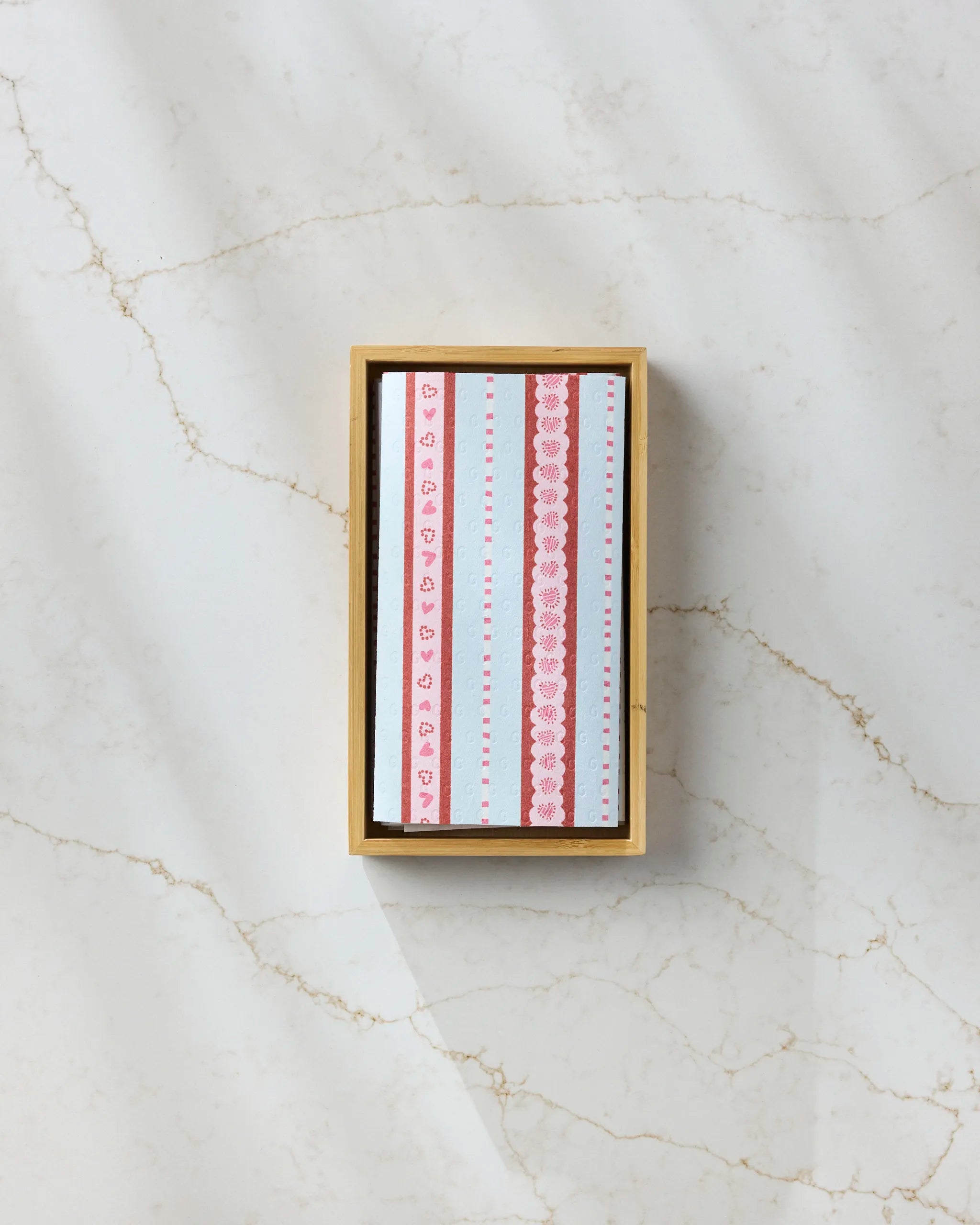 The “Dreaming of You” patterned note cards by Geometry, featuring red and pink hearts and stripes, add a charming touch to any space—perfectly paired with eco-friendly paper towels for a sustainable, thoughtful presentation.