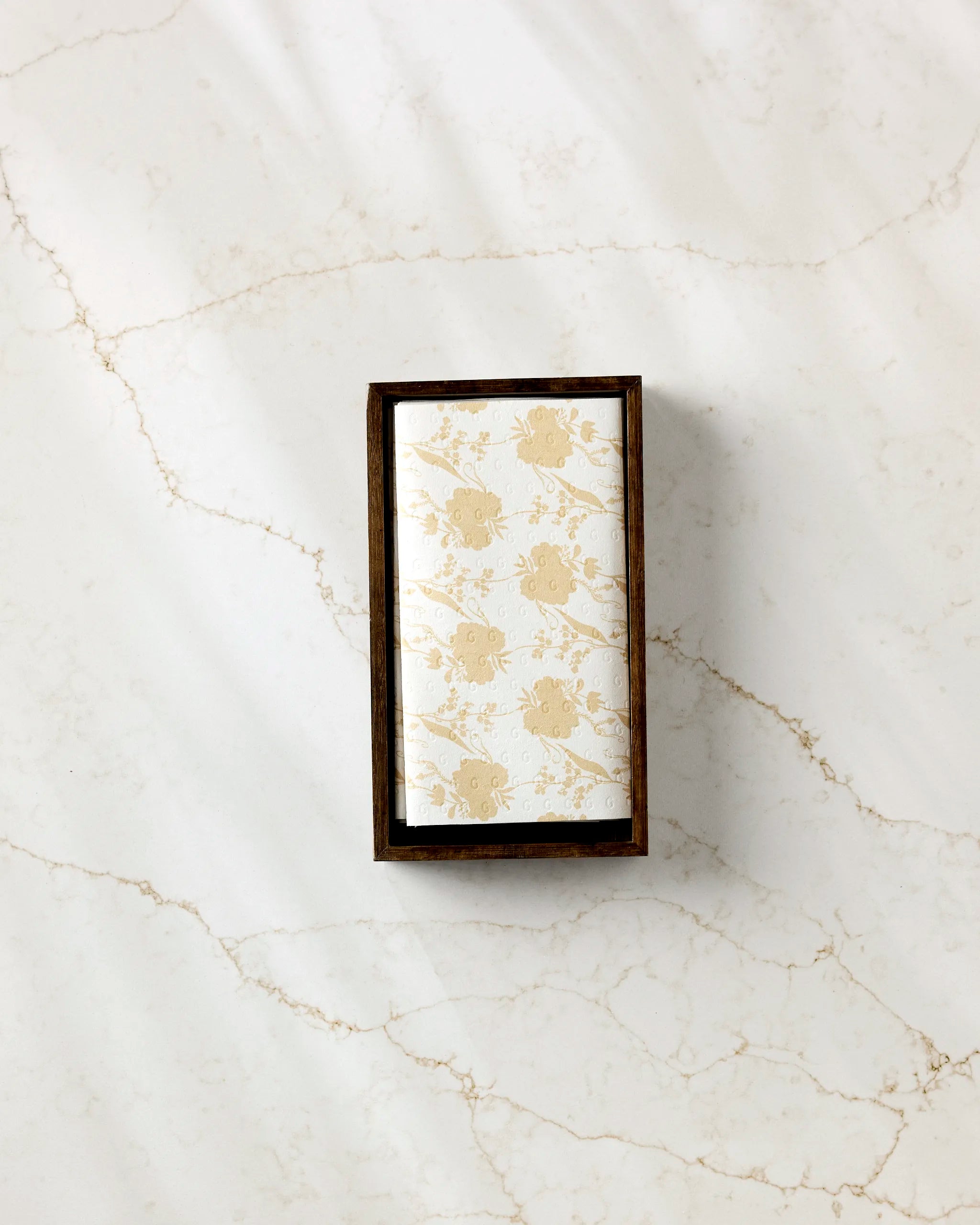 The GEOMETRY Eternal soap, wrapped in white and gold floral paper, rests in a dark wooden box on light marble, accompanied by folded eco-friendly paper towels for sustainable elegance.