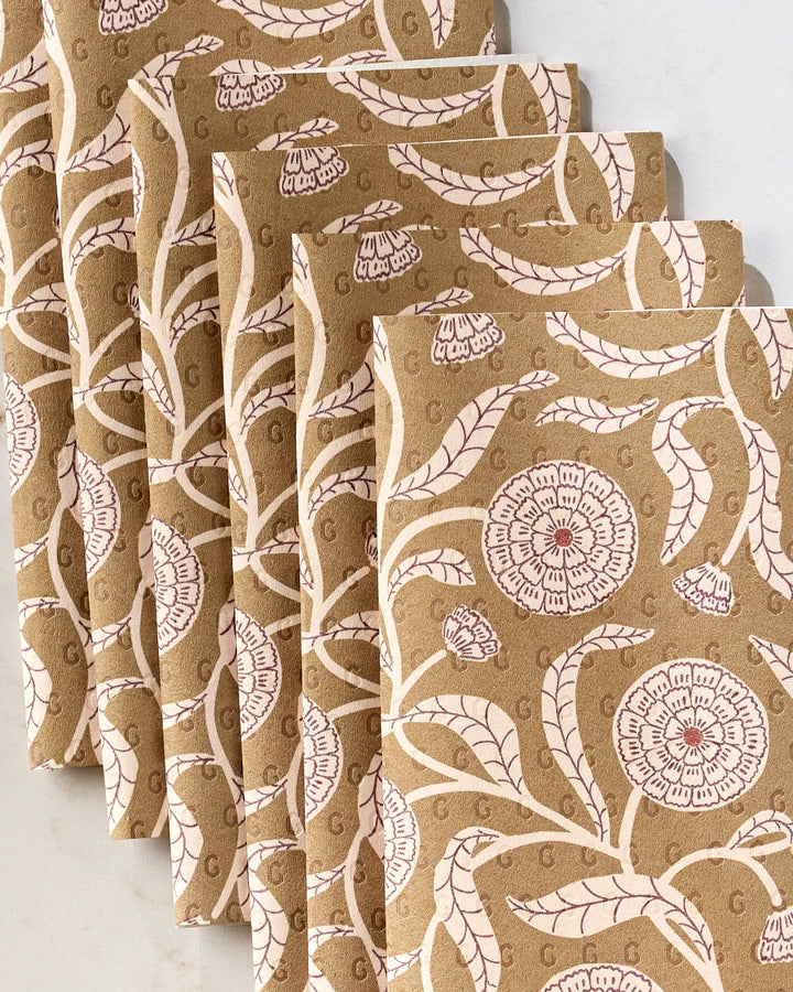 Five stacked "Falling Flowers" books by Teri the Butter feature brown covers with intricate pink and white floral patterns, shown overhead on a light surface—perfect for pairing with your eco-friendly kitchen towels.