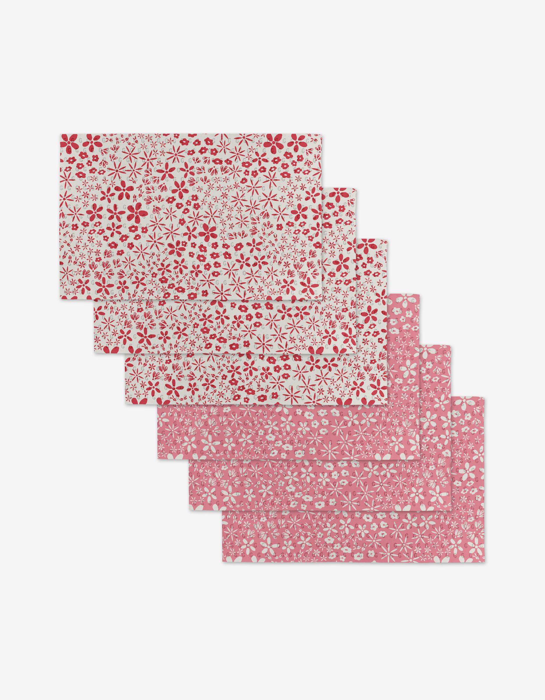 Six Fields of Flowers placemats by Hufton Studio, made from eco-friendly materials, are stacked: three have white backgrounds with red flowers; three have red backgrounds with white flowers in two floral patterns.