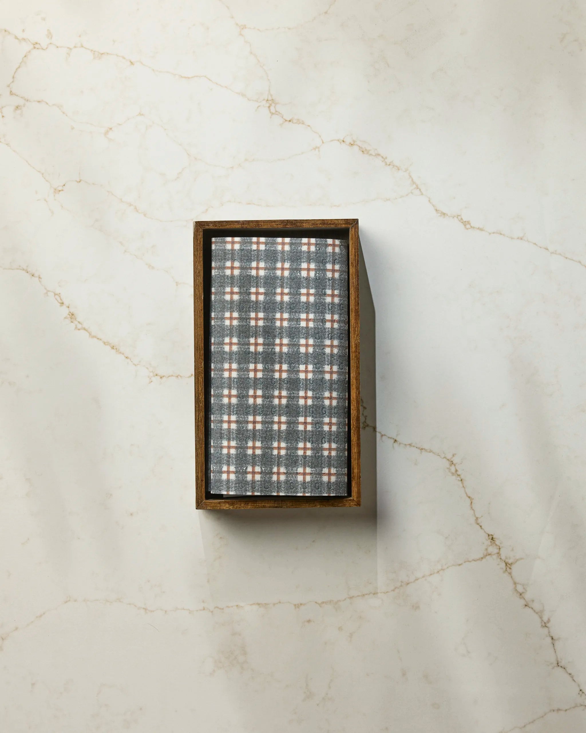 The Geometry Flint Hallowell is a rectangular wooden box with a gray, white, and orange plaid lid—ideal for storing eco-friendly kitchen or reusable paper towels—shown on a white marble surface.