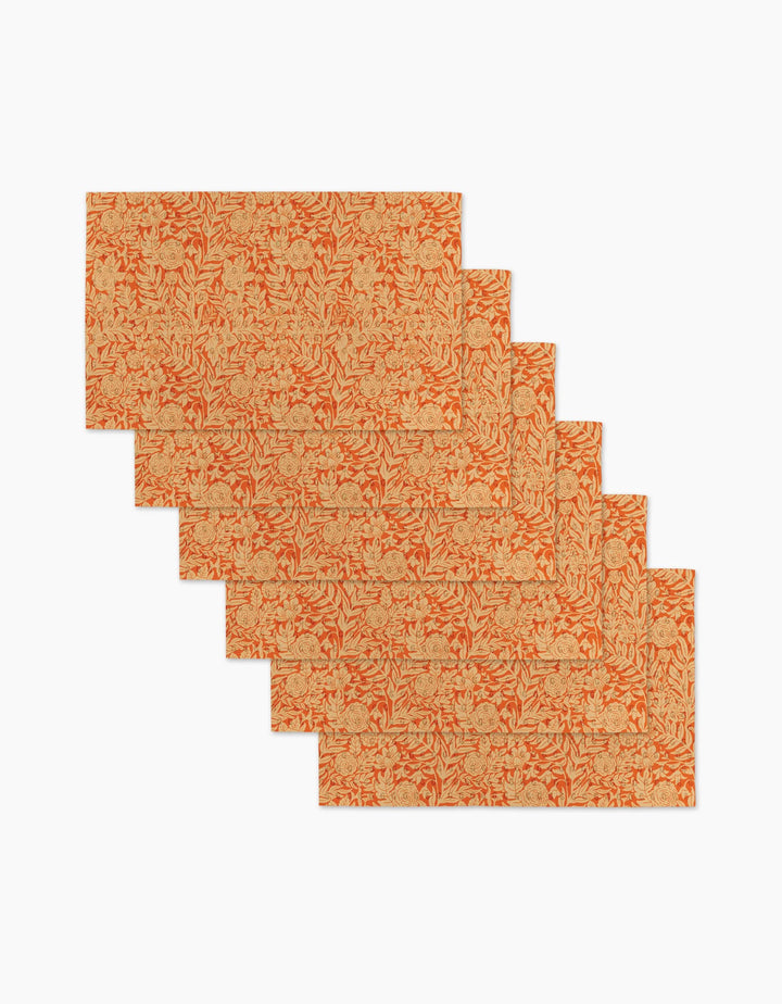 Six Florence rectangular placemats by Katie OShea, featuring an orange and beige floral pattern, are stylishly arranged in a staggered, overlapping layout on a white background.