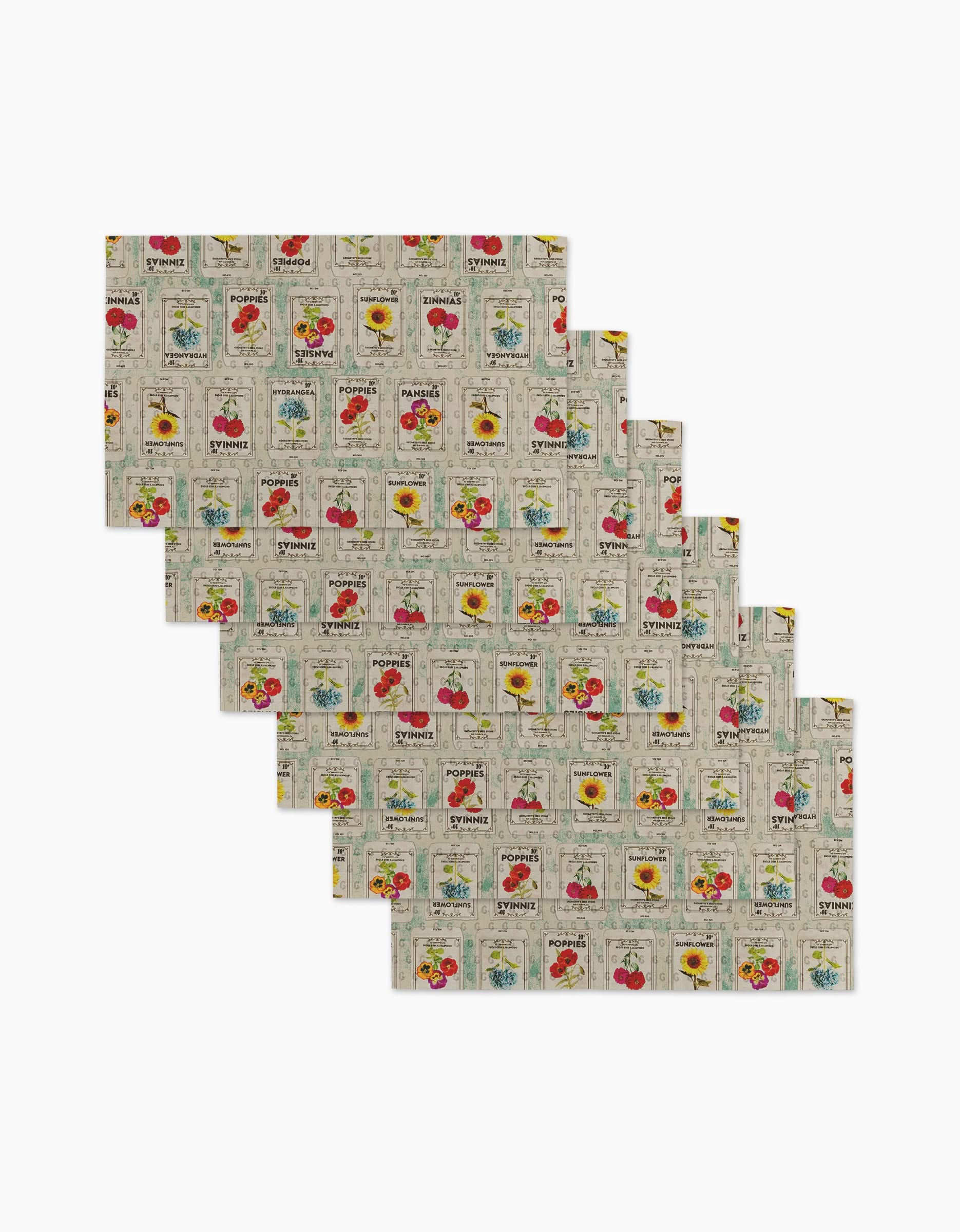 Six Flower Seed Packs rectangular placemats by Geometry showcase vintage vegetables, flowers, and garden tools in vibrant tones on beige—an eco-friendly alternative to paper towels.
