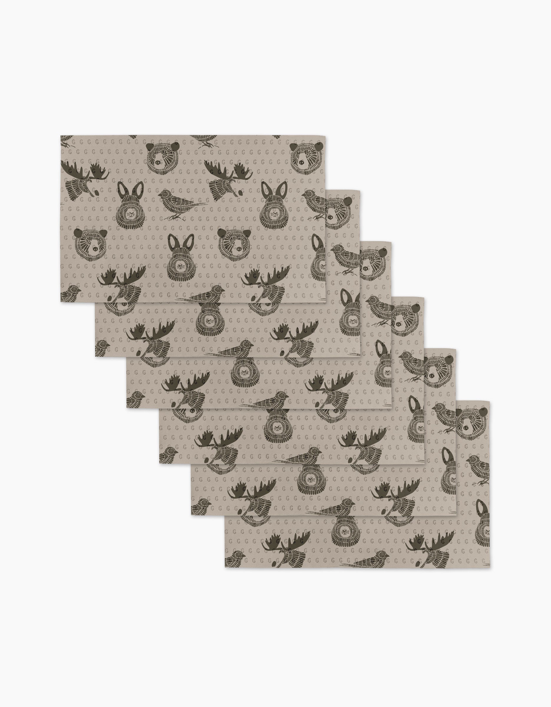 Six beige Forest Animals placemats by Rosa Kichline feature repeating cartoon faces of a bear, deer, and fox in dark brown. These eco-friendly kitchen towels are arranged in a slightly fanned-out stack.