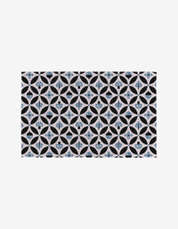 Forest Findings by Anette Heiberg features a repeating geometric tile pattern with blue and black circles, crosses, and petal shapes on a light background—a symmetrical, eco-friendly decorative motif.