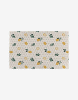 The Sara Mari Freshly Picked mat features a rectangular beige design with yellow lemons, green leaves, and gray Gs on a light background—crafted from recycled materials for an eco-friendly touch.