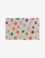 The Fruit Basket rug by Jennifer Bouron is a rectangular beige piece featuring gray G patterns and vibrant fruit and flower illustrations—a stylish, eco-friendly touch for any room.